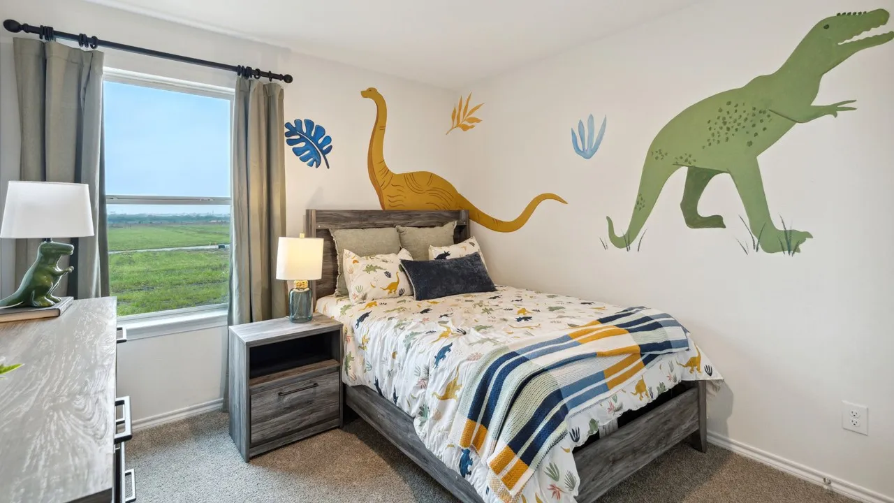 Bedroom featuring a large window, neutral carpeting, and a built-in wall outlet