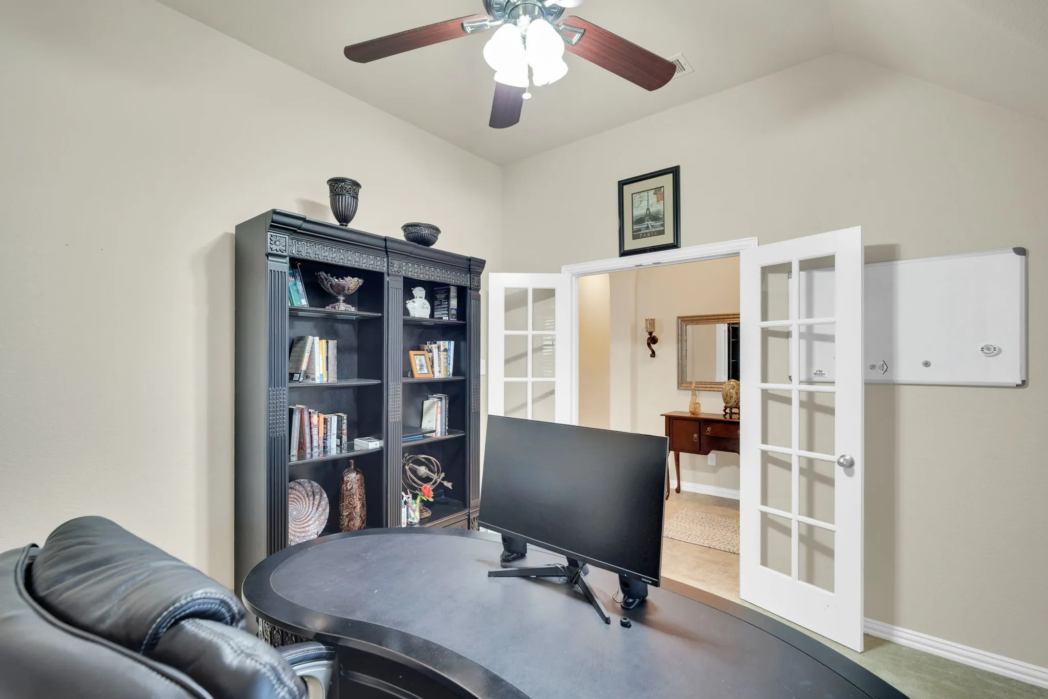 Vaulted ceiling room featuring light neutral wall paint, a ceiling fan, and white French doors