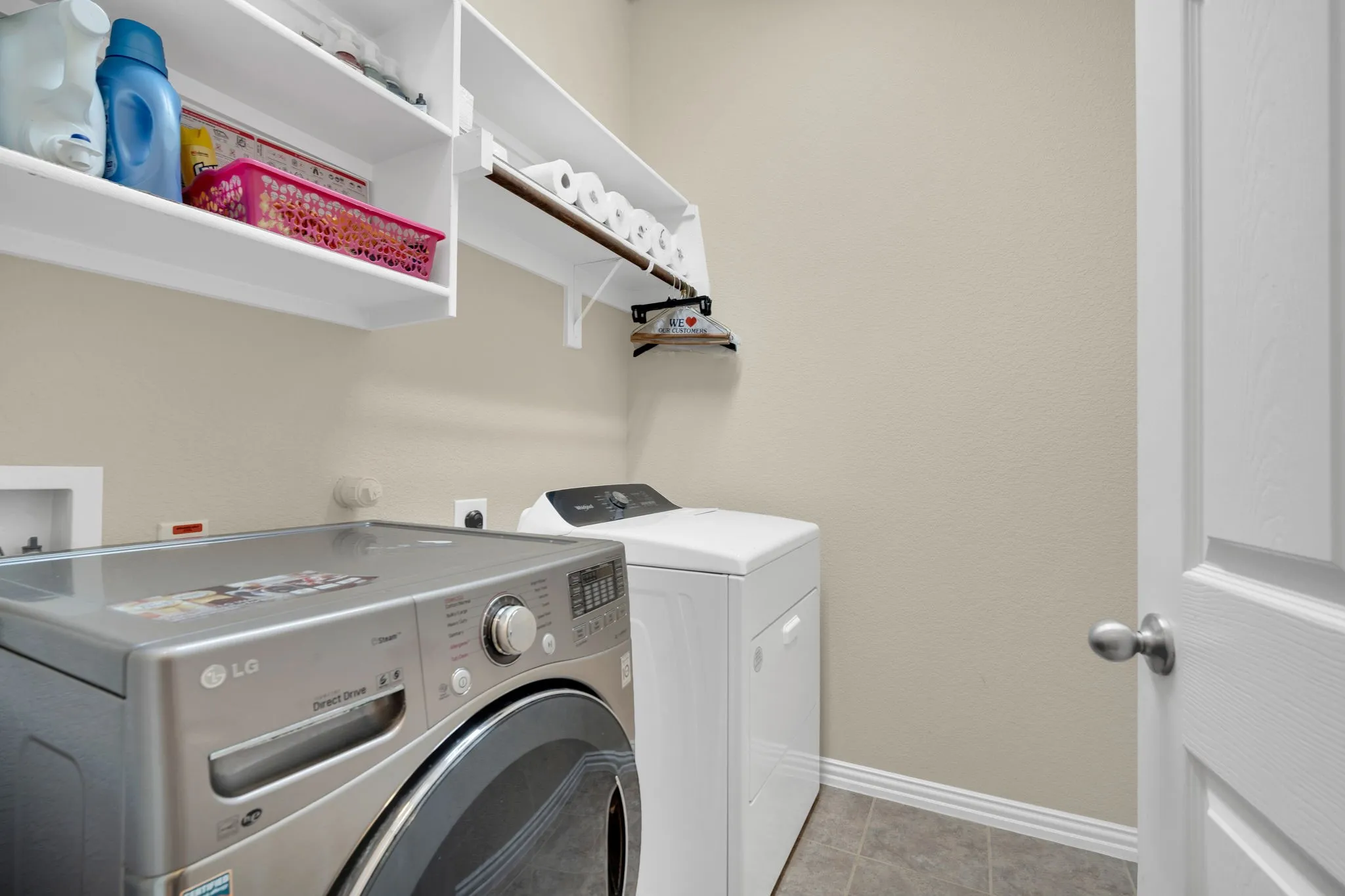 Laundry area featuring built-in shelving, a clothes rod, and tile flooring