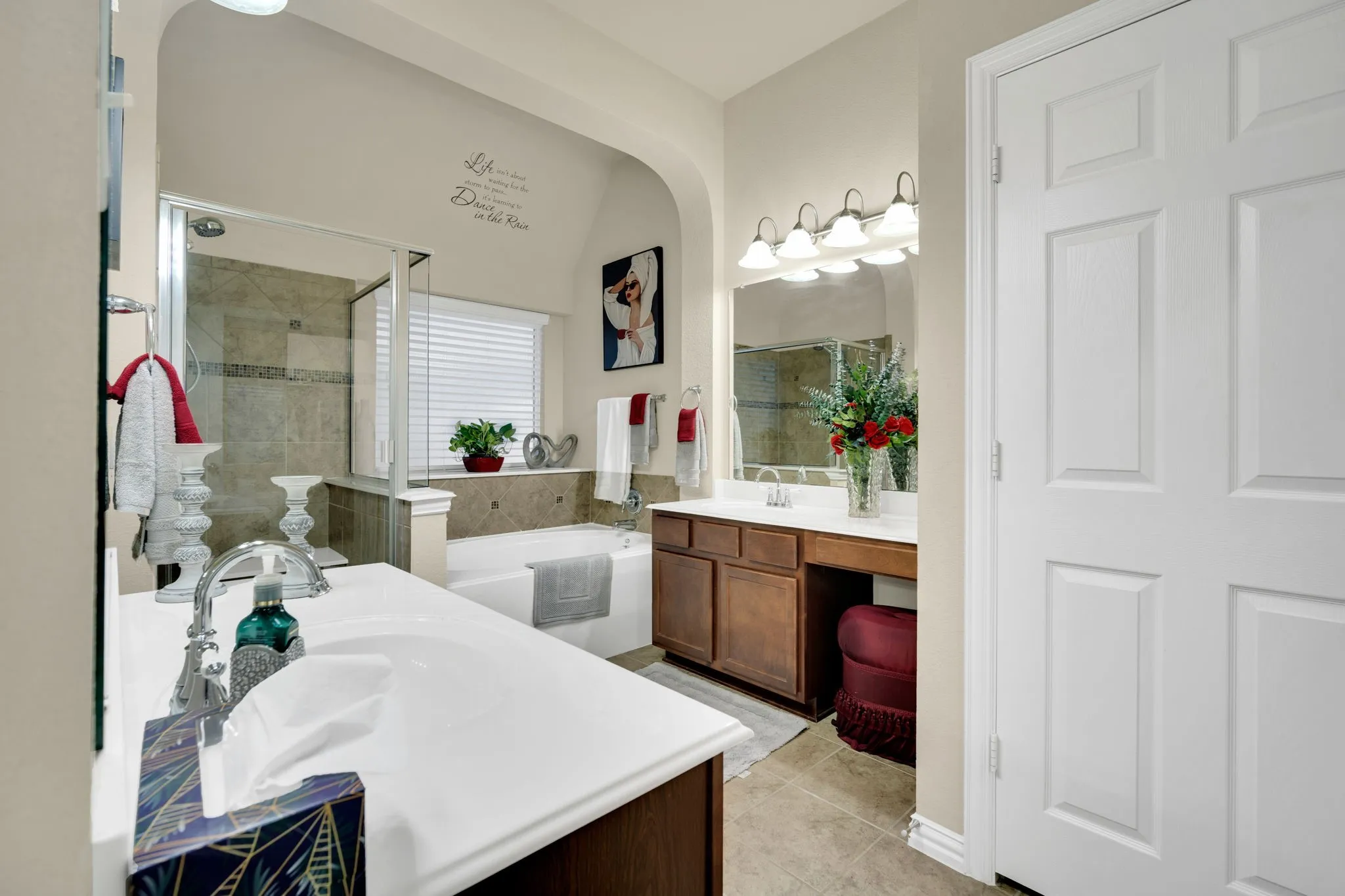 Bathroom featuring a double vanity with white countertops, wood-finish cabinetry, and an integrated makeup area