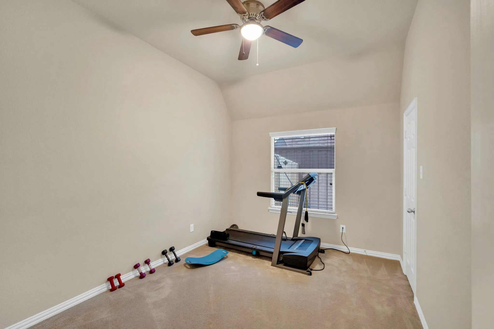 Versatile room featuring neutral carpet, light-toned walls, and a vaulted ceiling