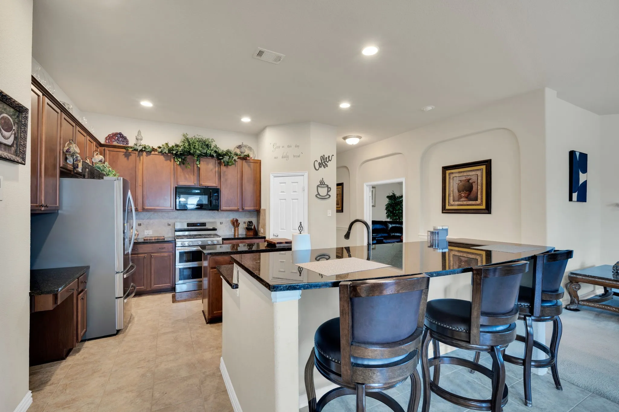 Spacious kitchen featuring dark wood cabinetry, granite countertops, stainless steel appliances, and recessed lighting