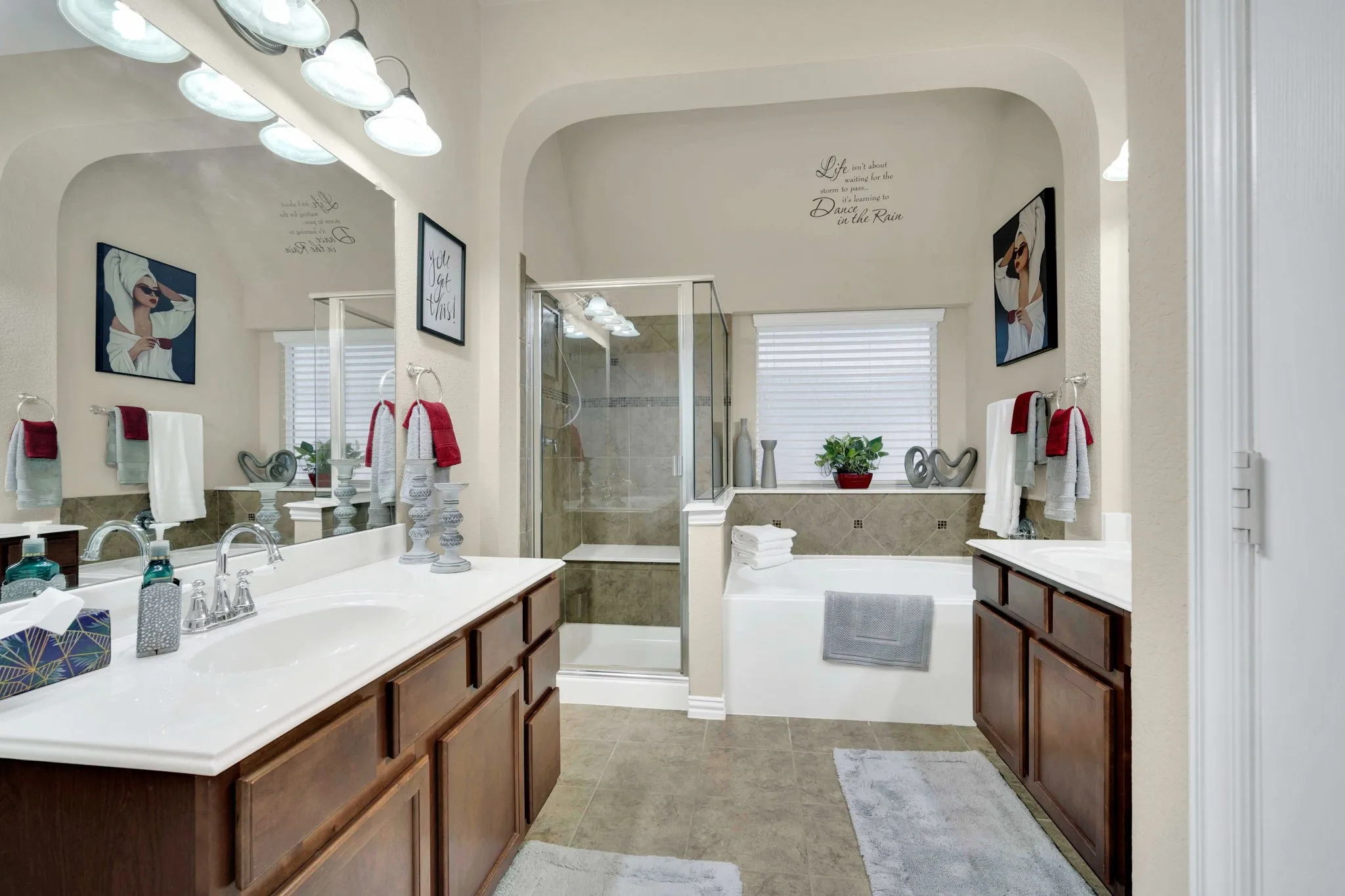 Spacious bathroom featuring a dual vanity with wood cabinetry, a built-in soaking tub, a separate glass-enclosed shower, and tile flooring