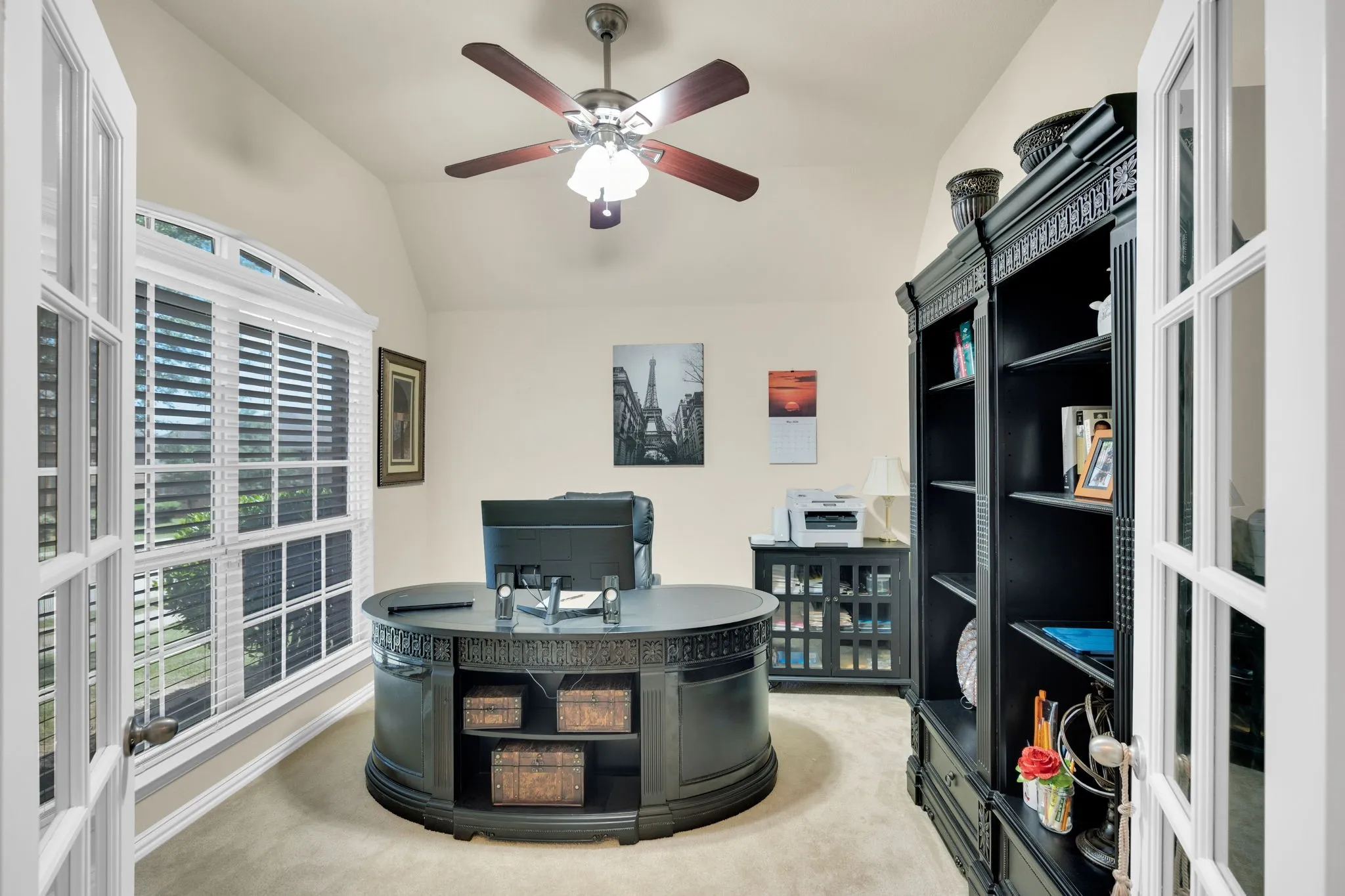 Room featuring vaulted ceiling, French doors, large arched window, ceiling fan, and built-in shelving