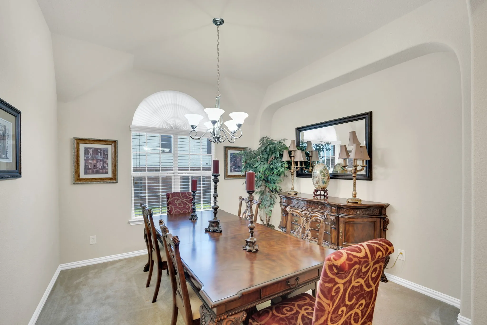 Dining room featuring a vaulted ceiling, arched window with horizontal blinds, overhead chandelier, and carpet flooring
