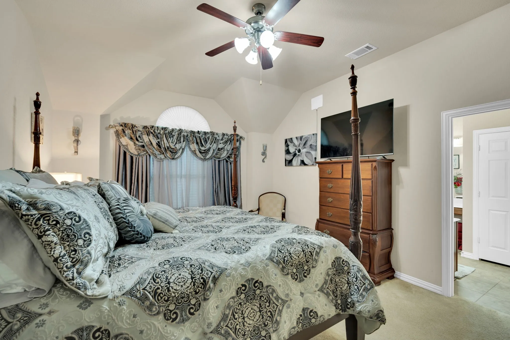 Vaulted ceiling bedroom featuring a ceiling fan with integrated lighting, arched window with decorative valance, recessed lighting, and carpet flooring