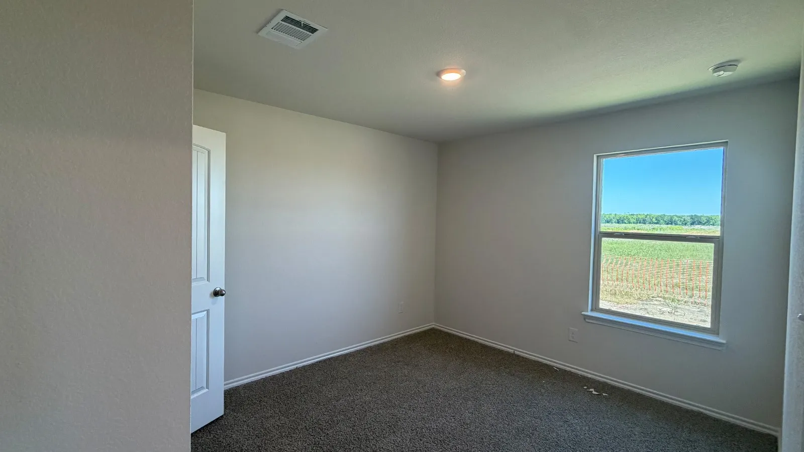 Carpeted room featuring a single window, recessed lighting, and a white paneled door