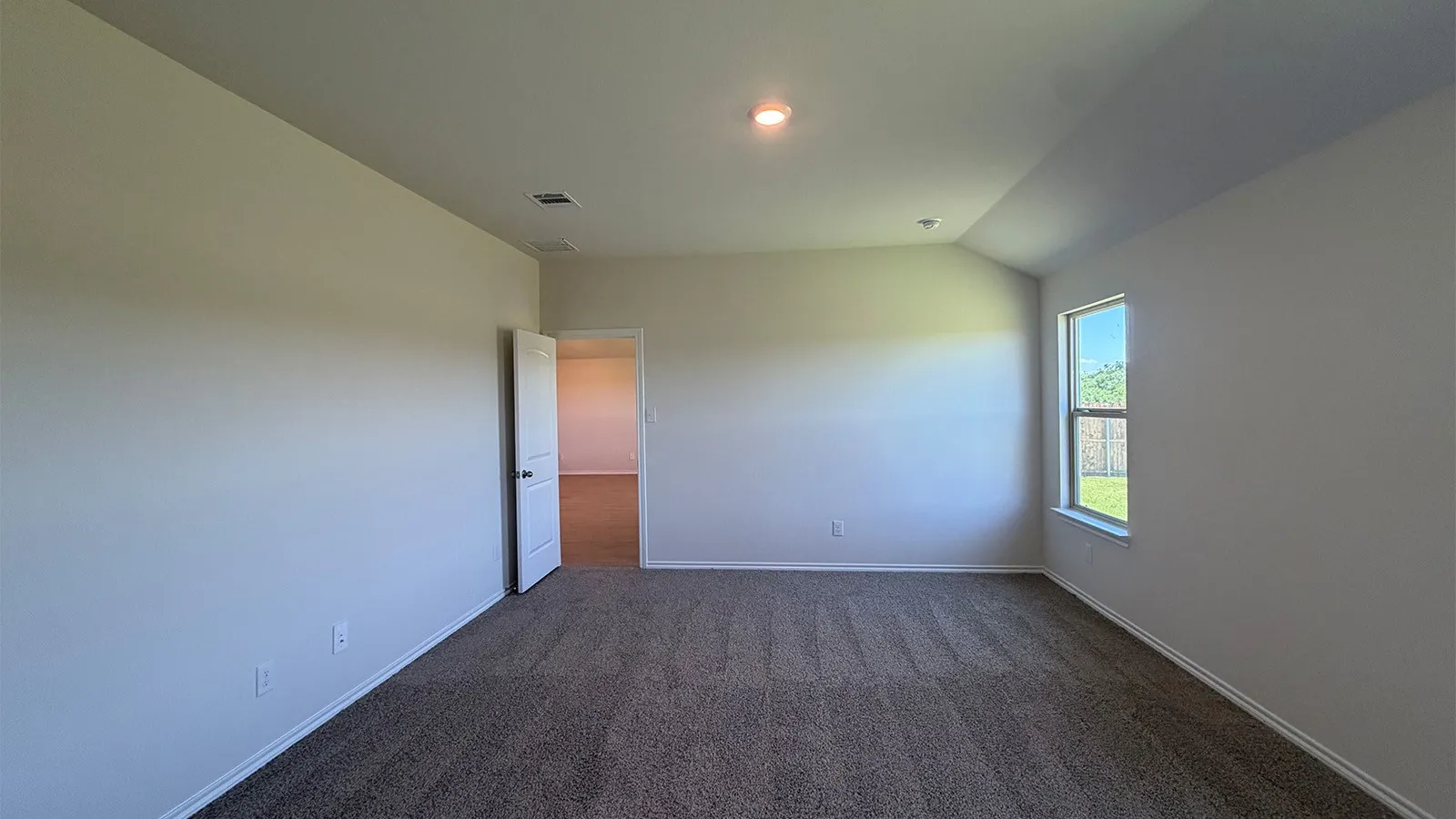 Neutral wall finishes, recessed lighting, and a single window offering natural light