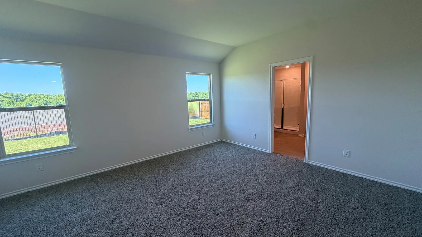 Spacious room with vaulted ceilings and gray carpet flooring
