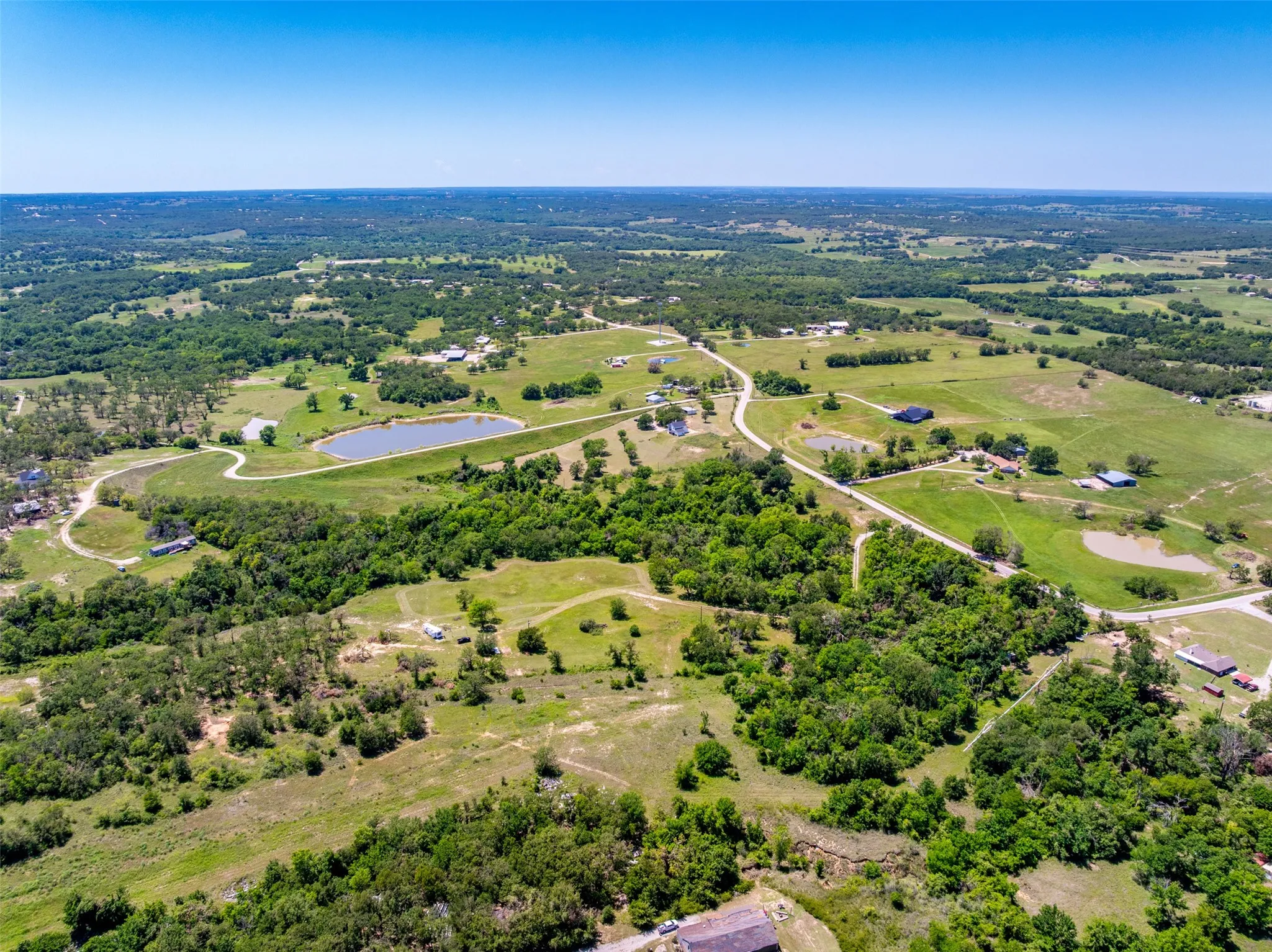 Expansive rural landscape featuring rolling green terrain and mature tree coverage