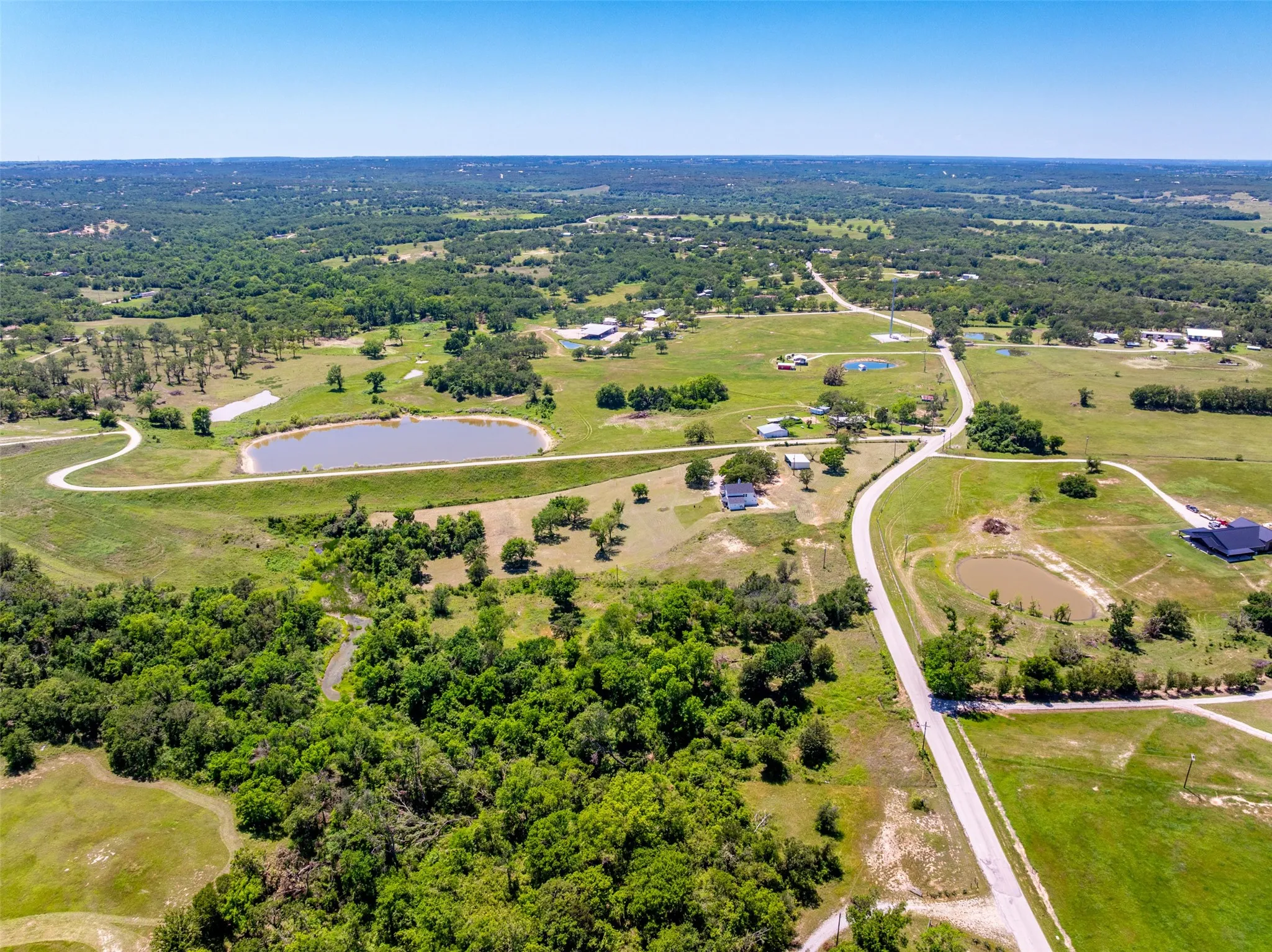 Expansive rural landscape featuring extensive green acreage and multiple ponds