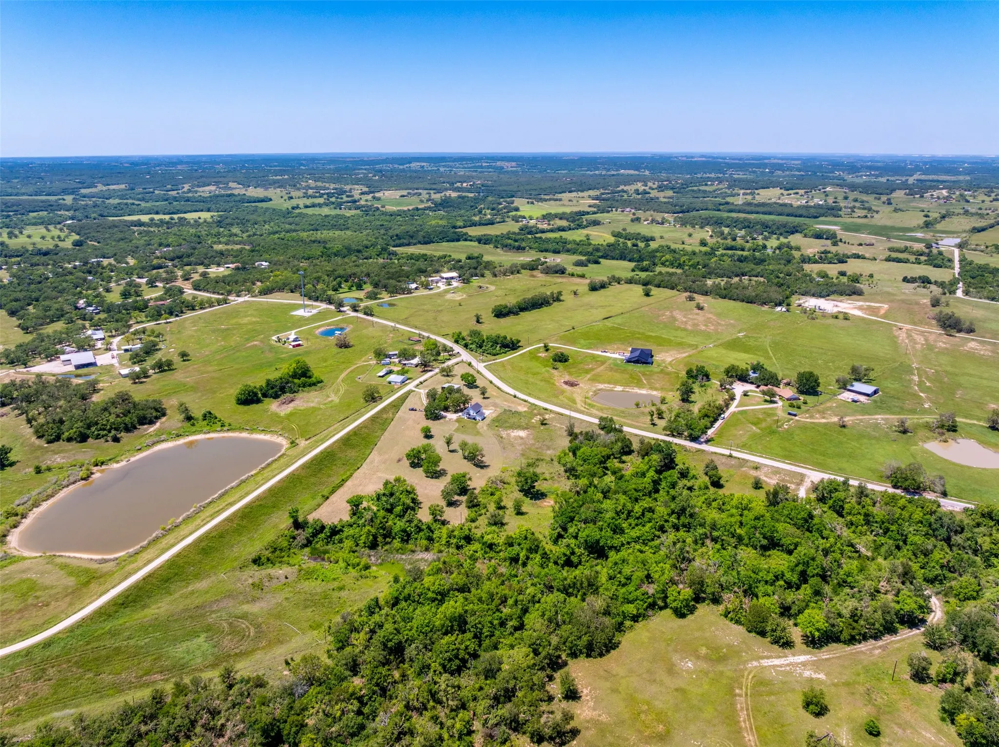 Expansive open land with scattered trees and multiple visible ponds