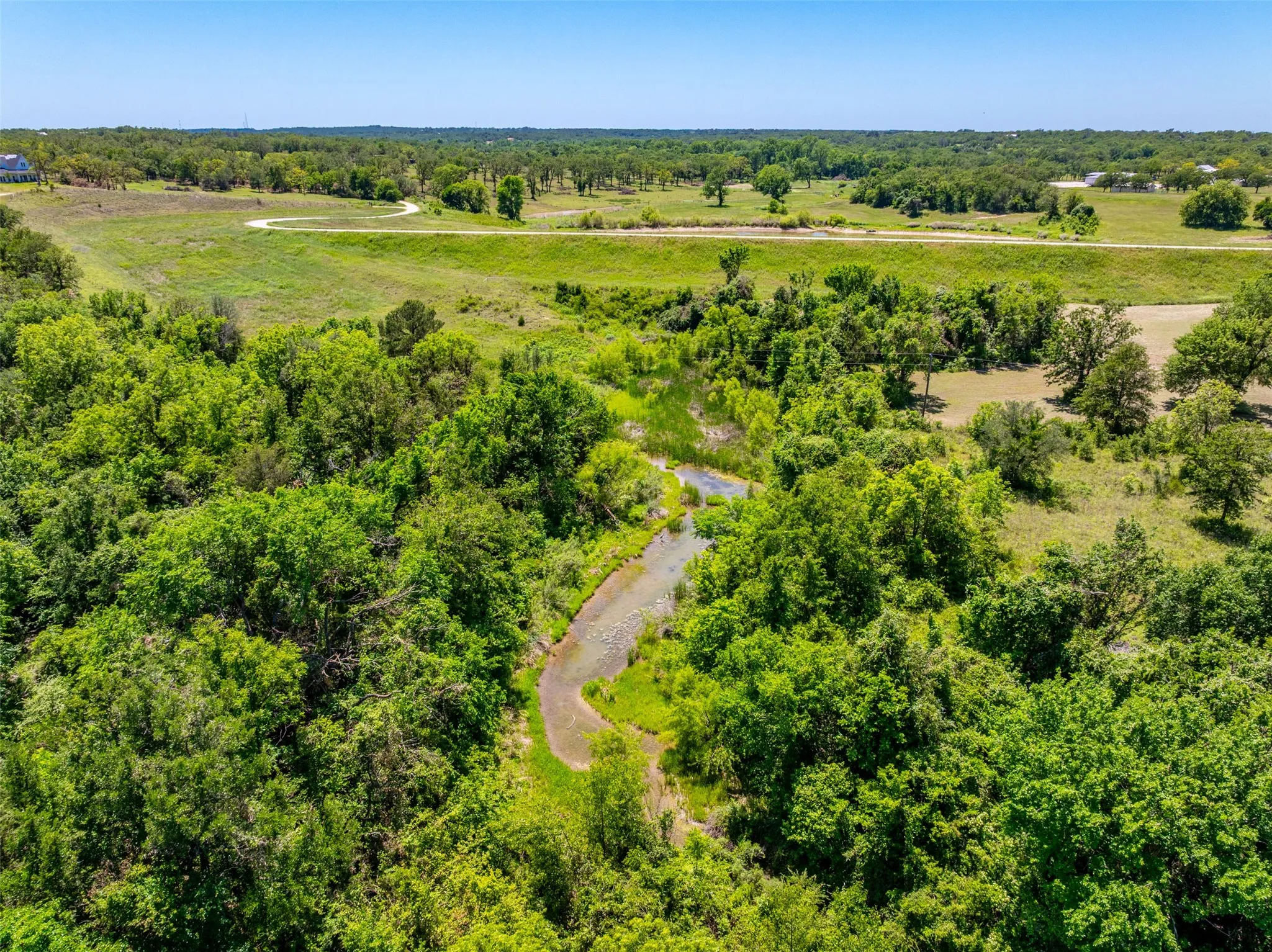 Expansive verdant landscape featuring a winding waterway, mature tree coverage, and open clearings