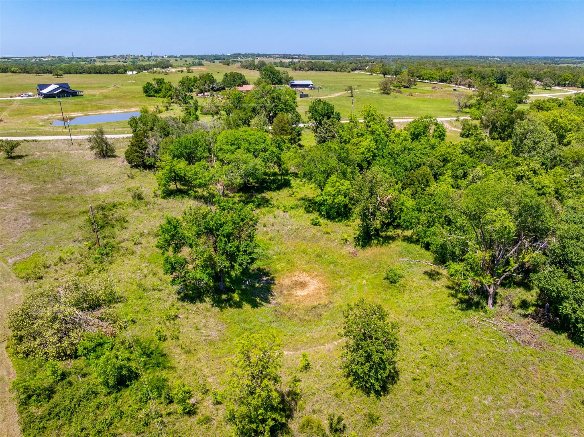 Expansive rural landscape featuring a mix of open grassy areas and mature tree coverage