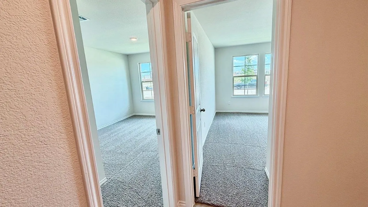 Two separate rooms featuring light neutral wall paint, gray textured carpeting, white baseboards, and white window frames