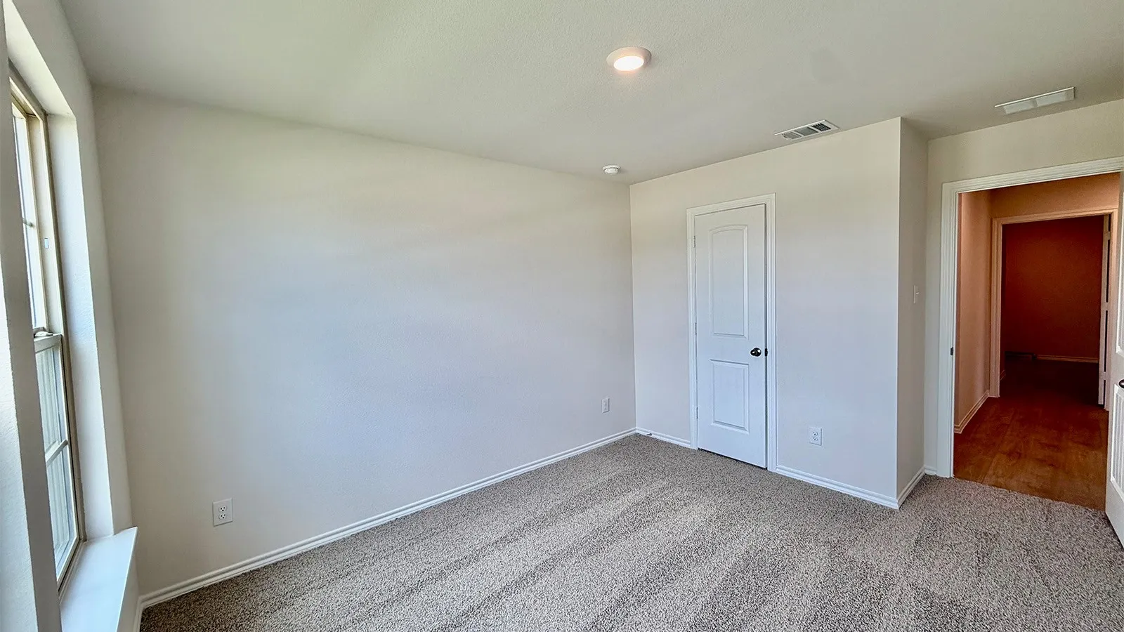 Carpeted room featuring a white interior door, a single window, and recessed lighting
