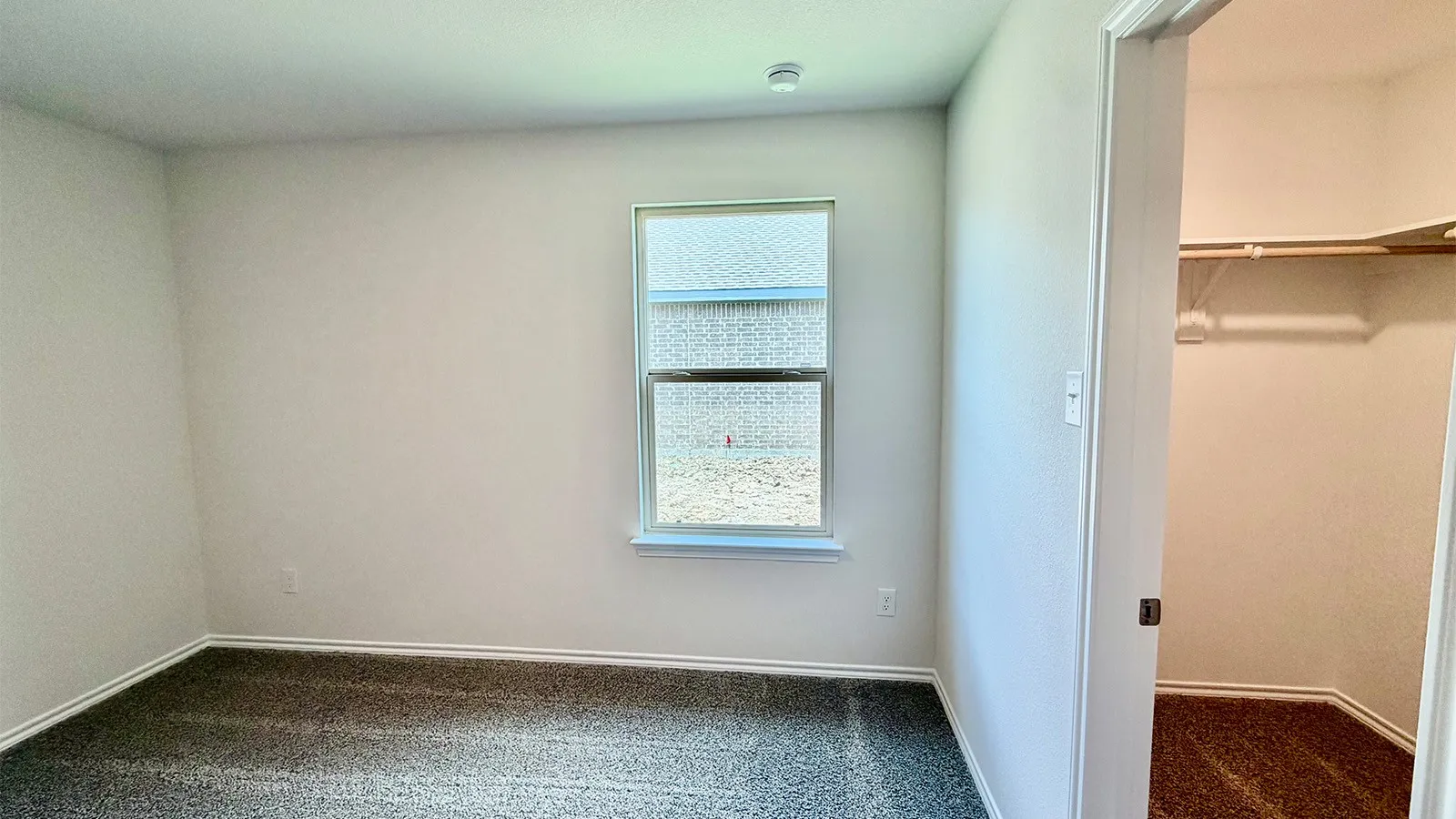 Room featuring neutral wall finishes, carpet flooring, a single window, and a built-in closet with shelving
