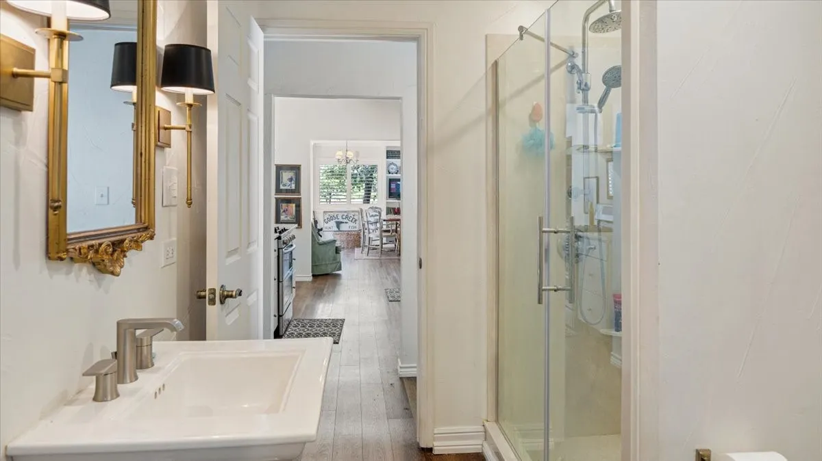 Bathroom featuring a vanity with a white basin and brushed nickel faucet, an ornate gold-framed mirror, and brass sconces with black shades