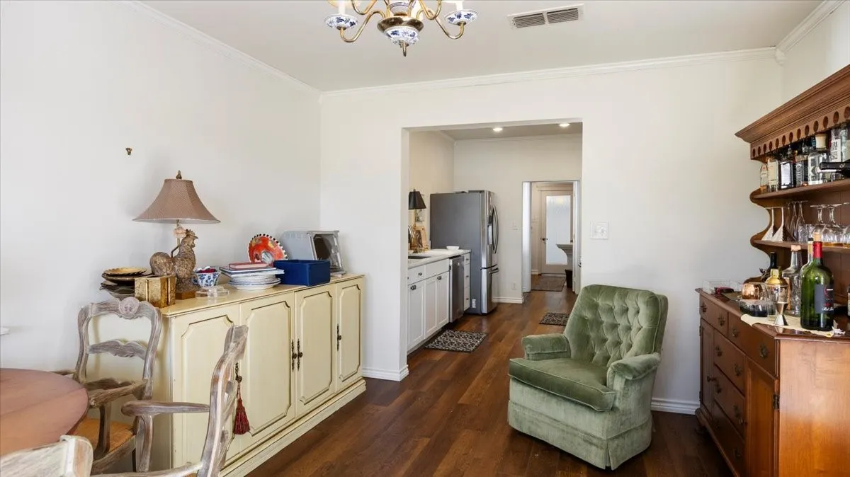 Open-concept living area featuring wood-finish flooring, white walls, and crown molding