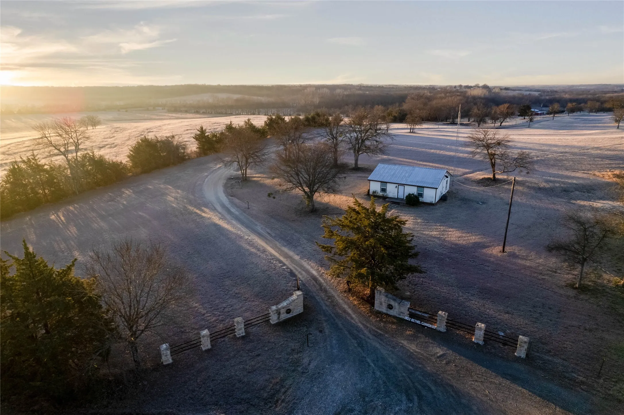 Expansive rural property featuring a white single-story residence with a metal roof