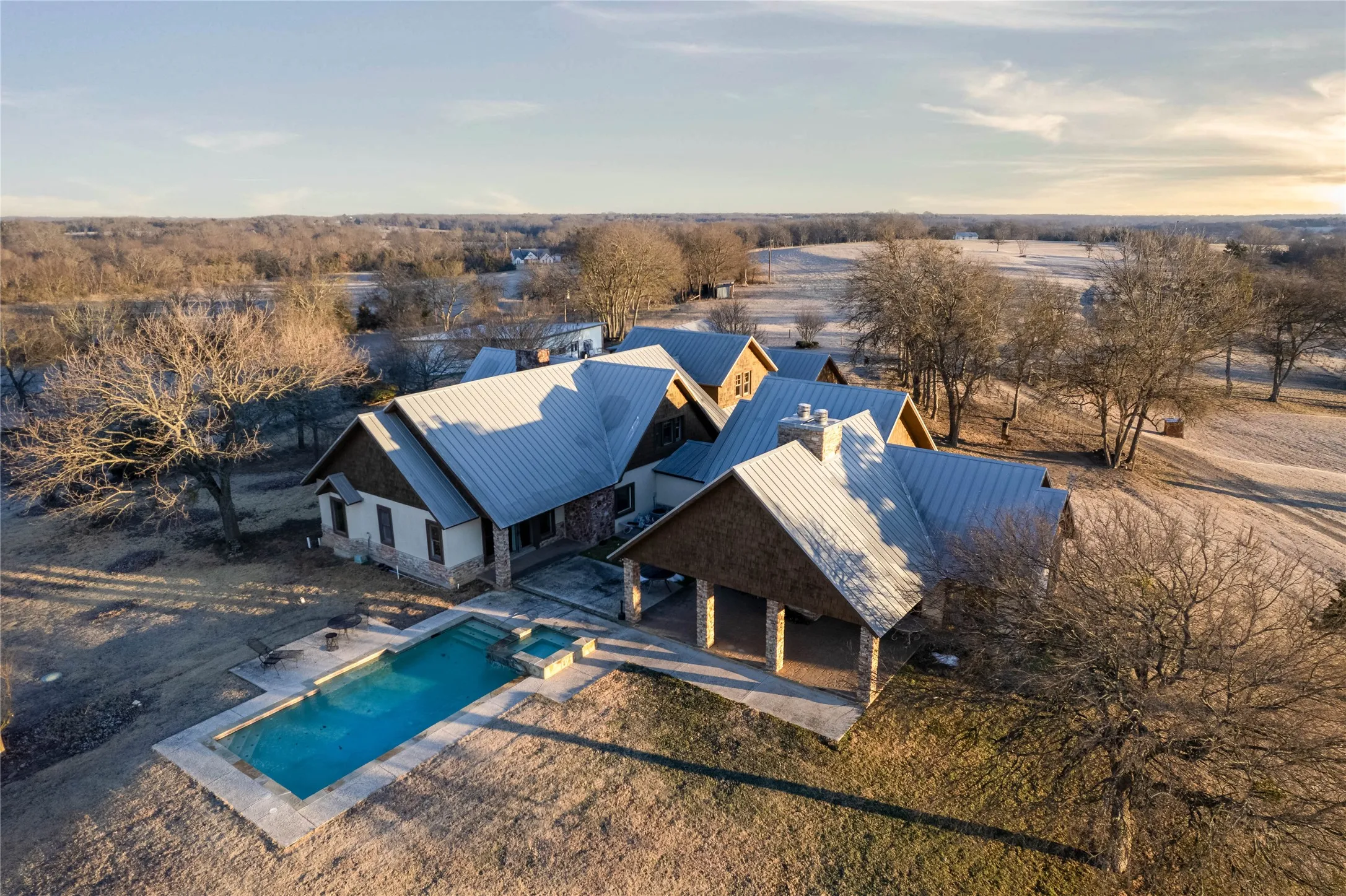 Expansive property featuring a multi-gabled main residence with a metal roof and stone veneer