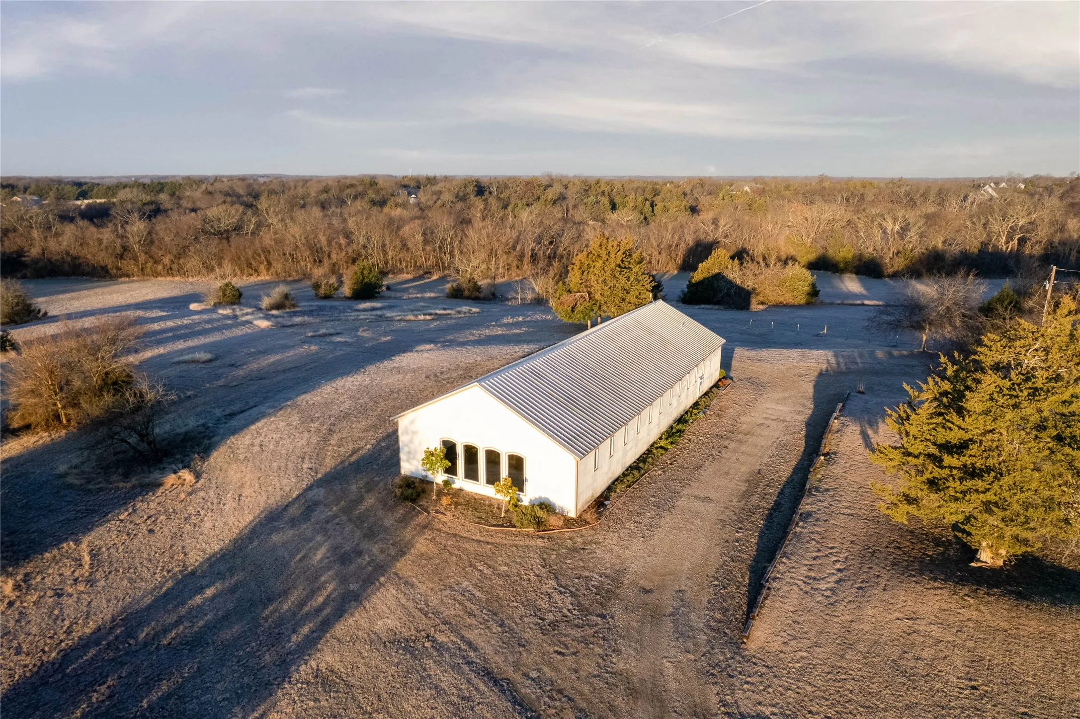 White-sided structure featuring a corrugated metal roof and multiple windows with dark shutters