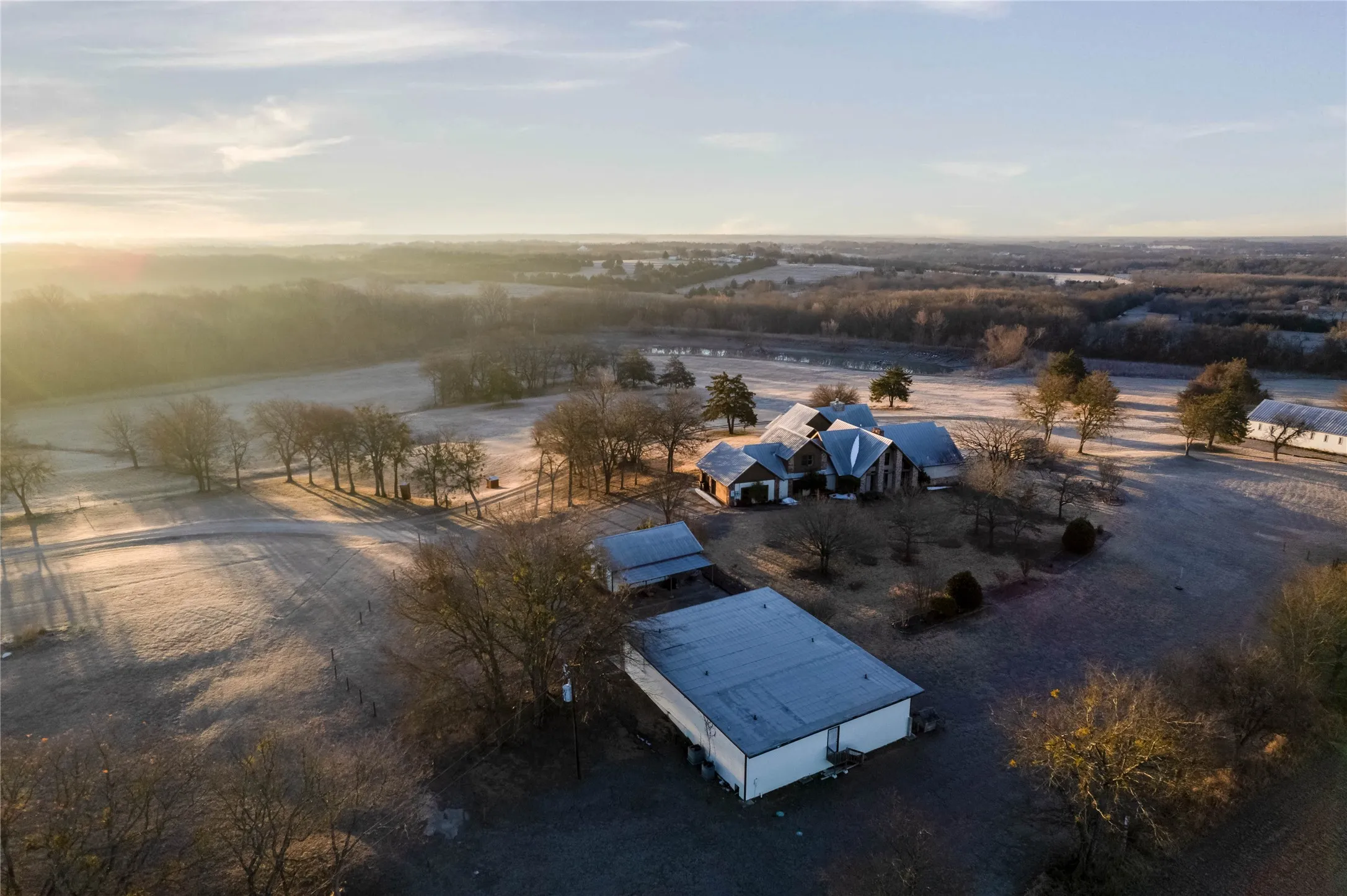 Spacious property featuring multiple structures, including a main residence with a multi-gabled roofline, several outbuildings, and expansive surrounding land