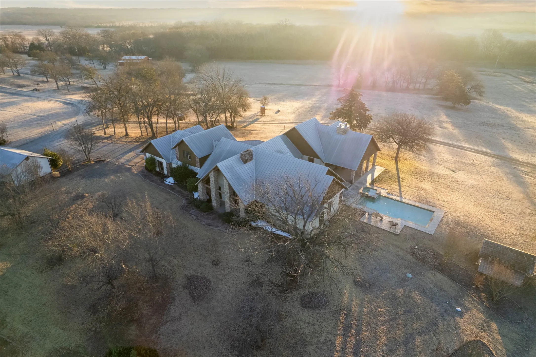 Expansive property featuring a multi-gabled home with a metal roof and stone veneer accents