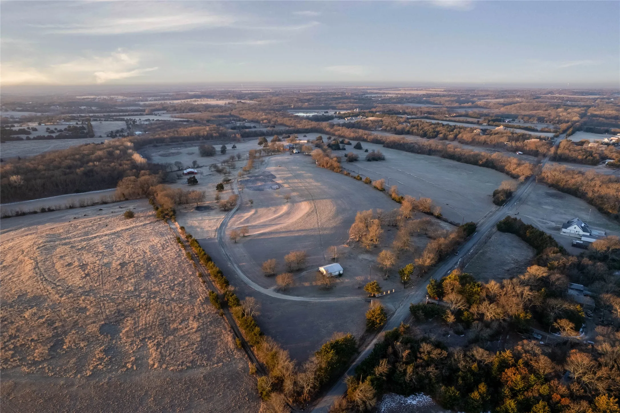 Sprawling rural landscape featuring expansive open fields and wooded areas