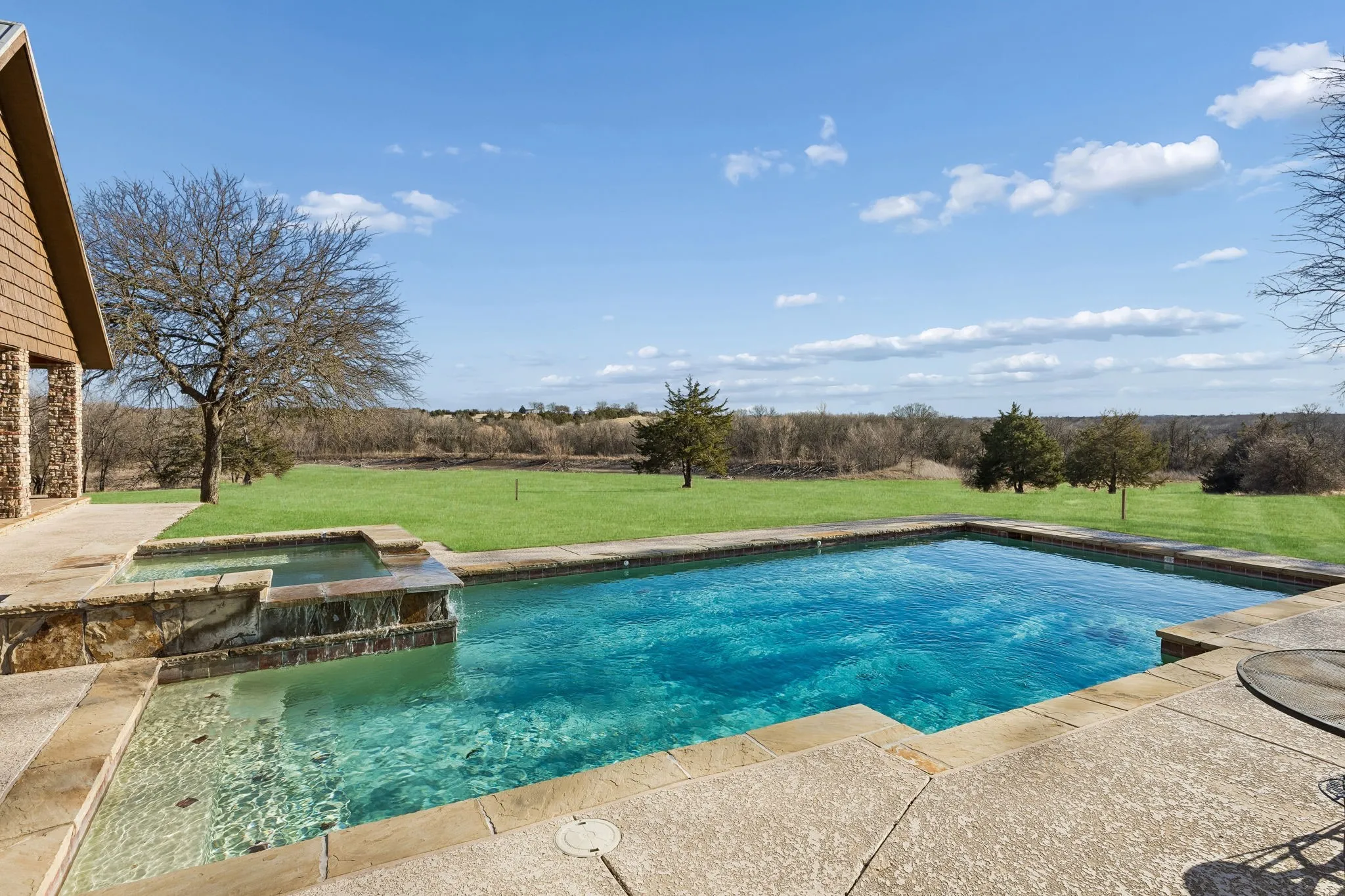 Backyard oasis featuring an in-ground swimming pool and an integrated stone-clad spa with a waterfall feature