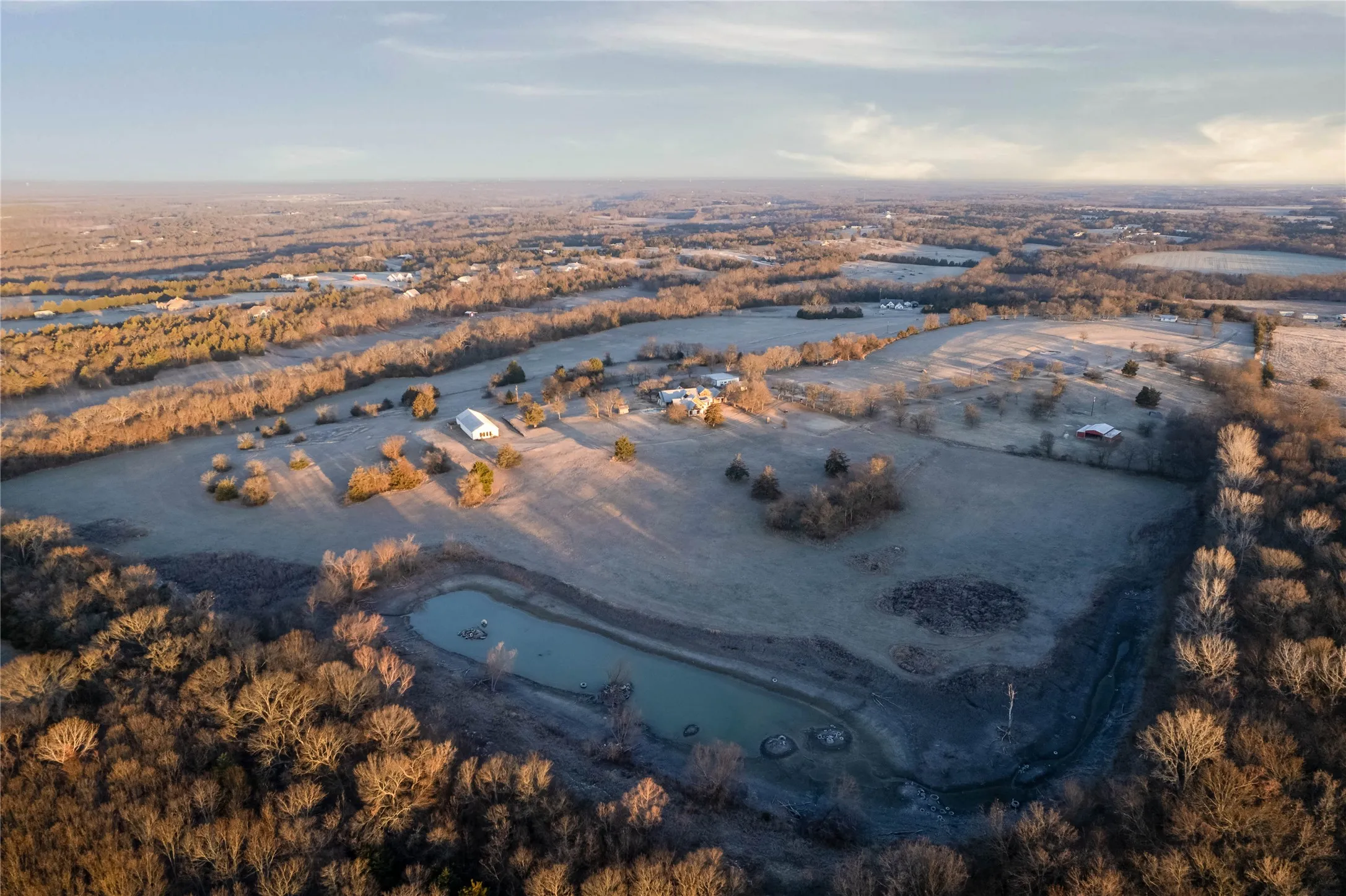 Expansive acreage featuring a private pond, multiple structures, and extensive treelines