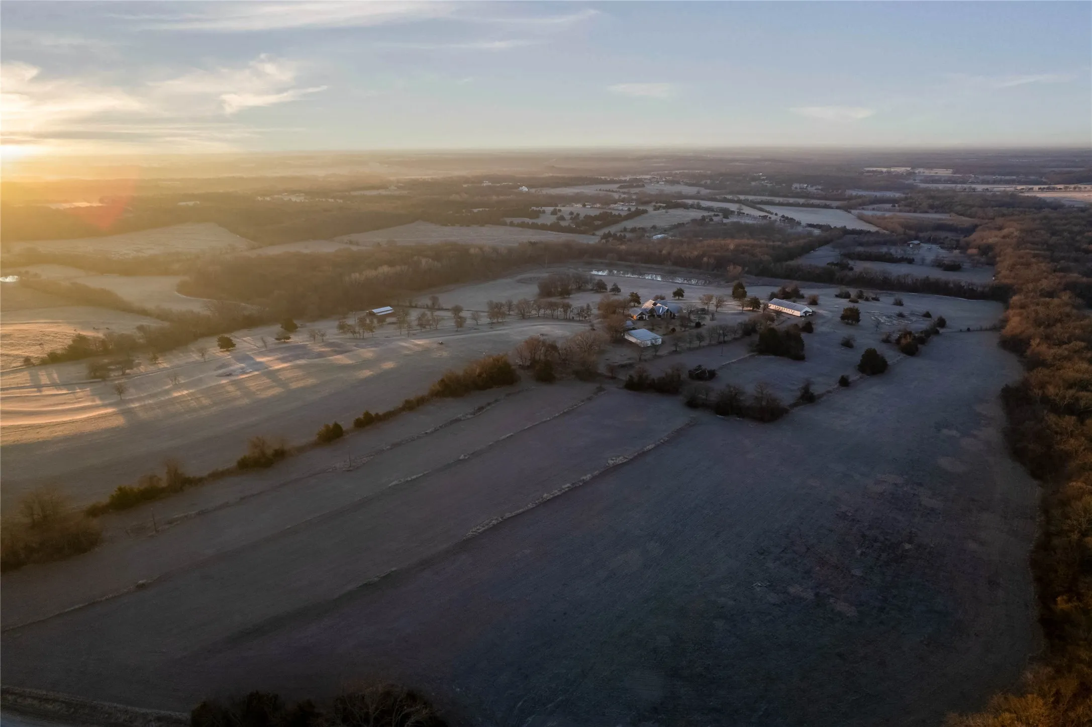 Expansive land parcel featuring multiple structures, open fields, and wooded areas