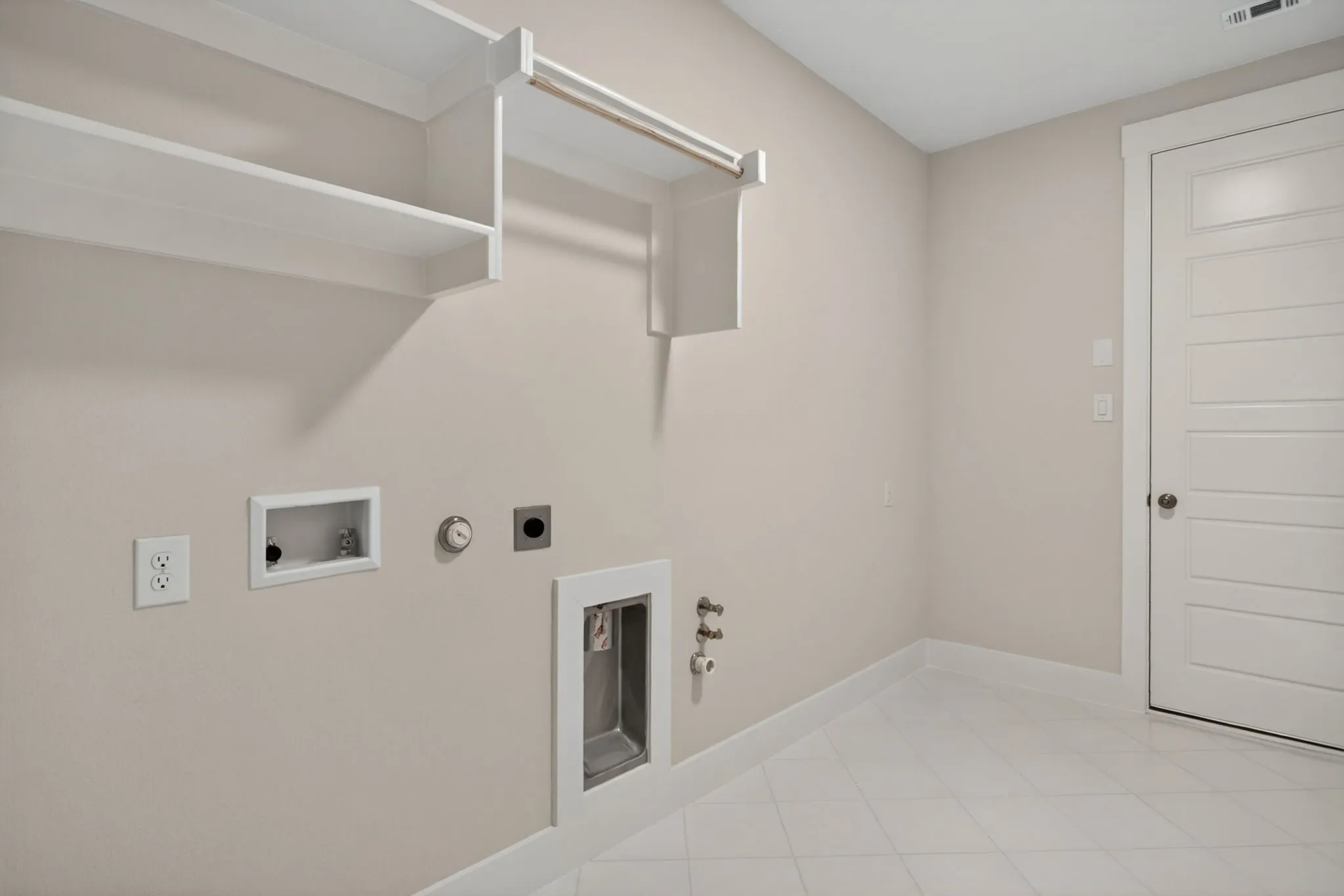 Utility room featuring light neutral wall paint, white trim, white shelving, an integrated hanging rod, and diagonal tile flooring