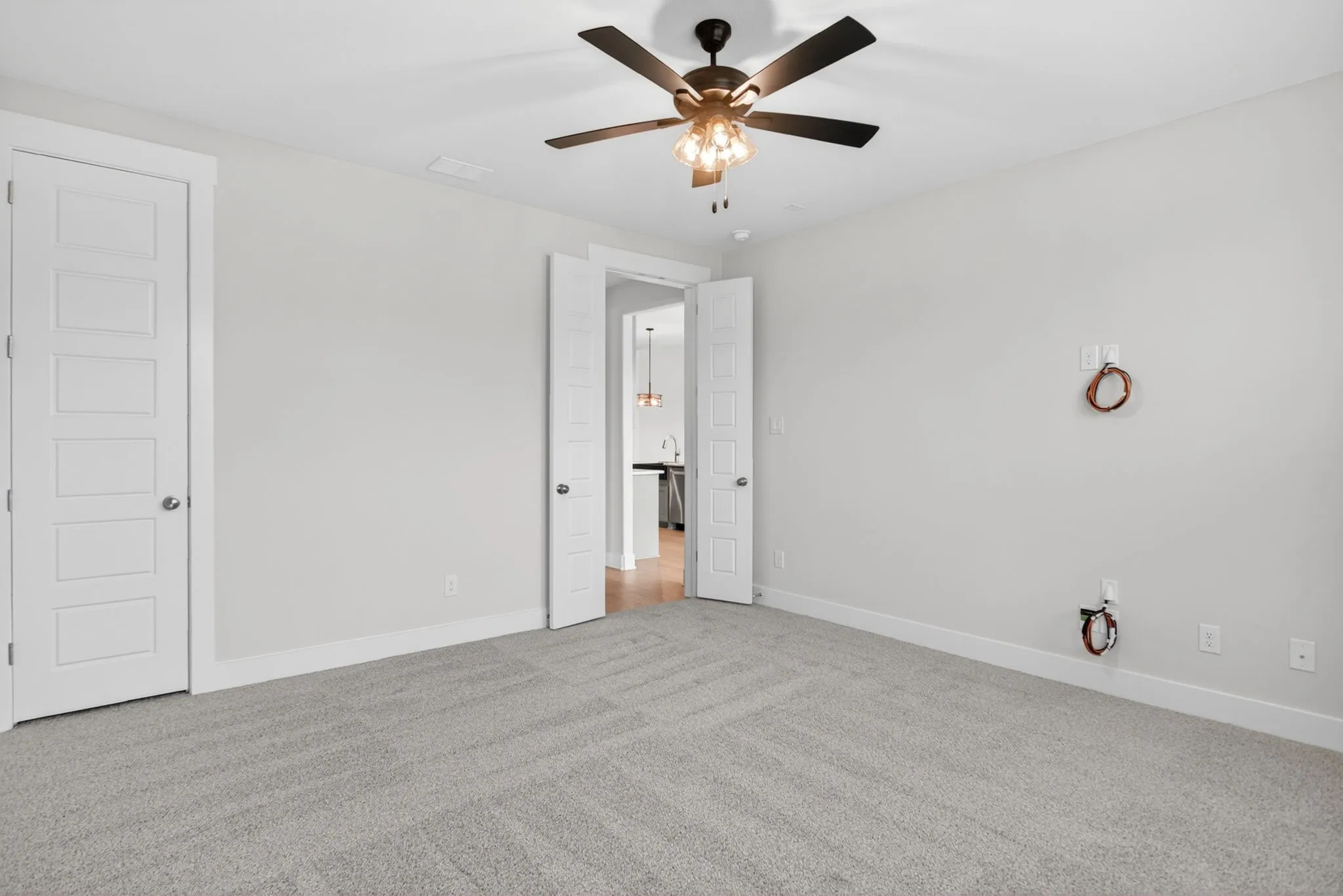 Spacious interior room featuring light gray carpet, neutral wall paint, and white trim