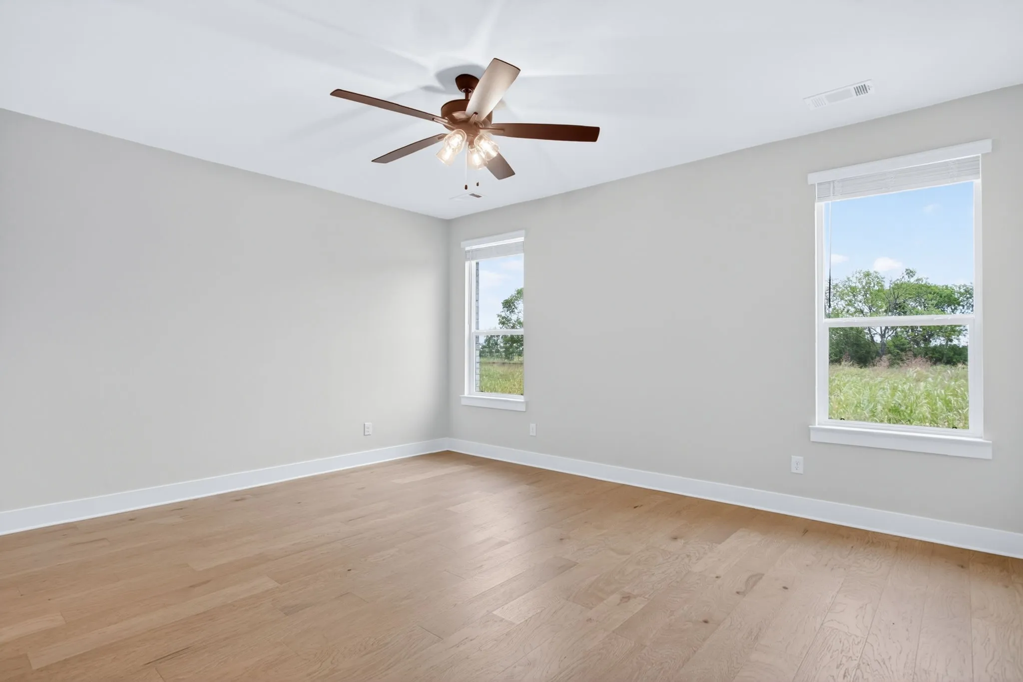Spacious room featuring wood-finish flooring, light gray walls, and white trim