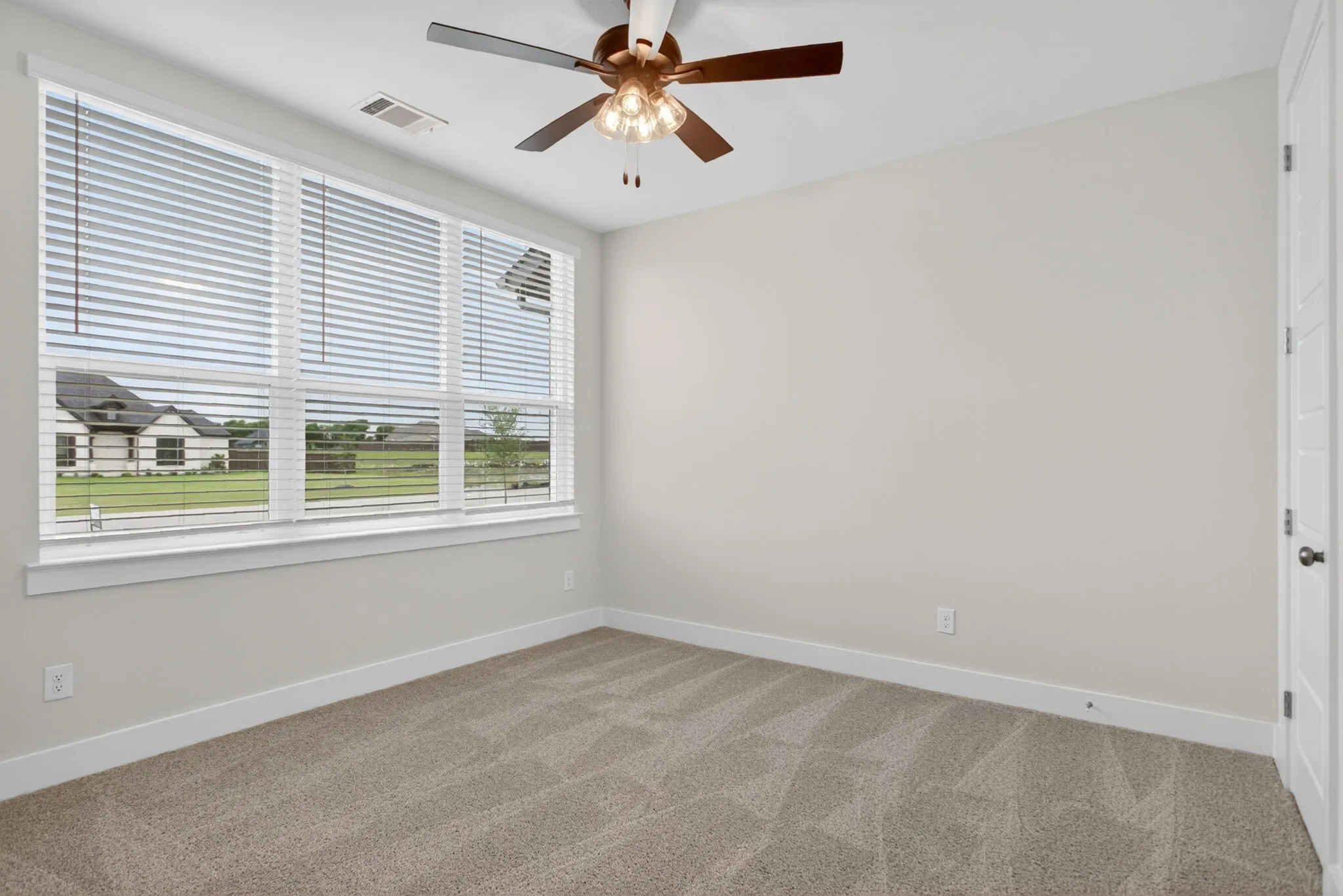 Expansive window with white blinds, neutral carpeting, and light-toned walls