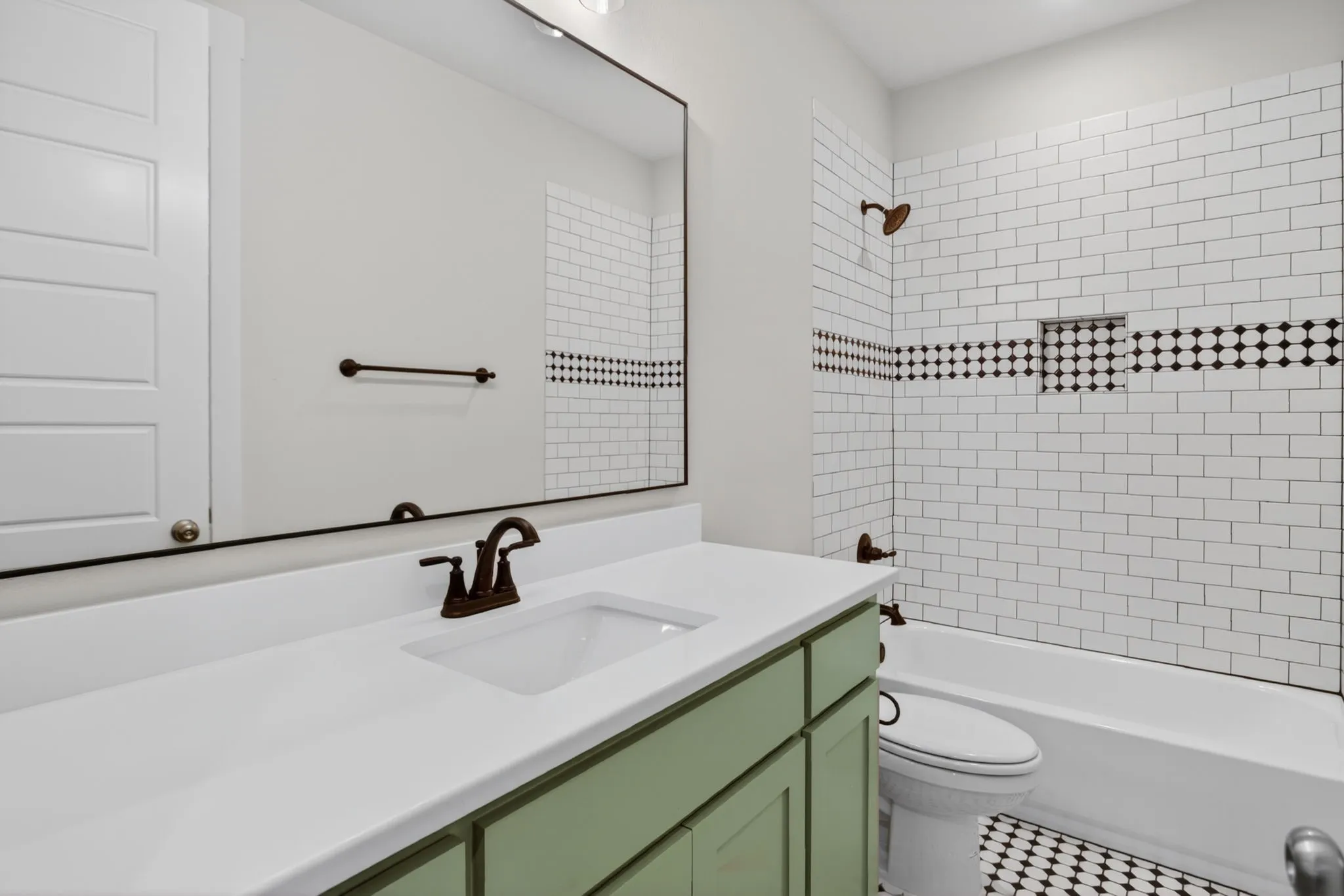 Bathroom featuring a single basin vanity with a light green base, white countertop, and dark-finished faucet