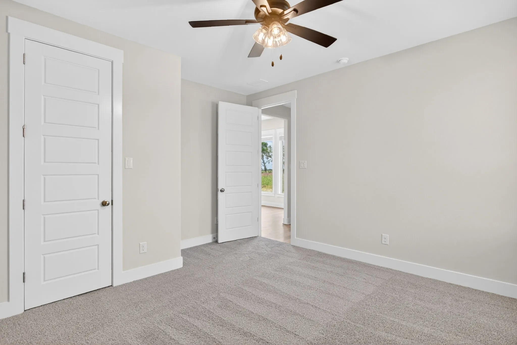 Spacious room featuring light gray carpeting, neutral wall finishes, and a contemporary ceiling fan with integrated lighting