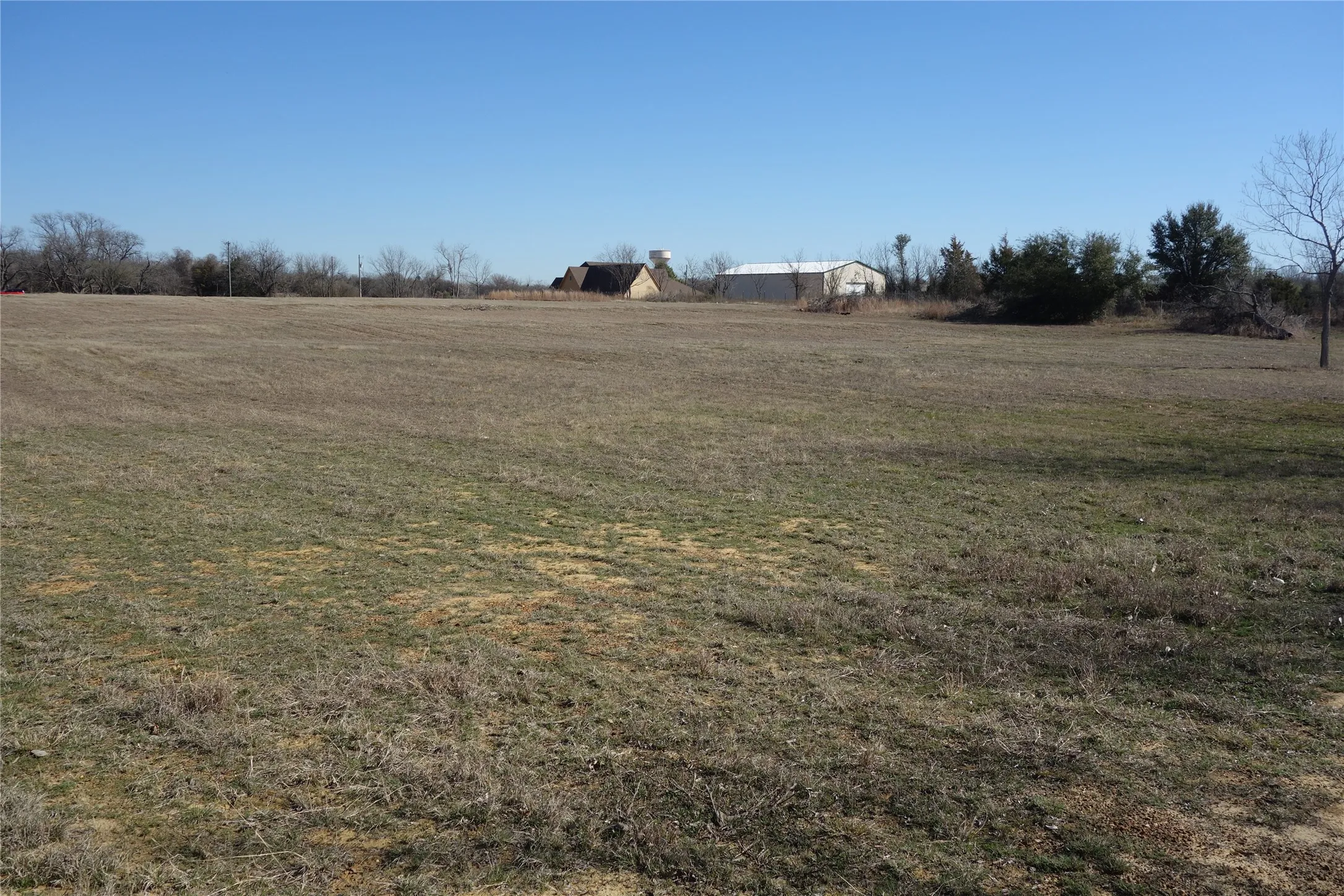 Expansive open field with visible distant structures and a clear sky