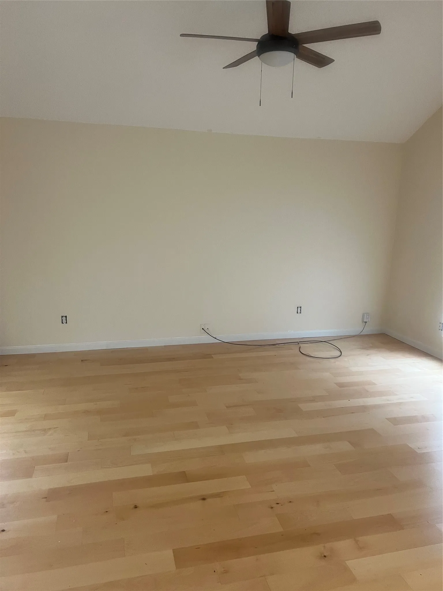Hardwood-finish flooring with light-toned walls and a ceiling fan with integrated lighting