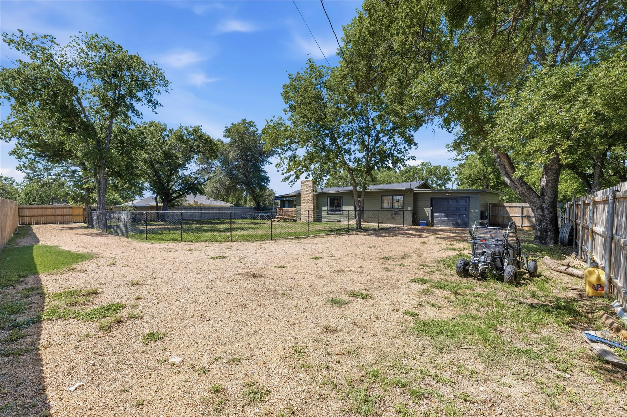 Back yard is fenced in with black fence and drive way has a gate to the left of the photo