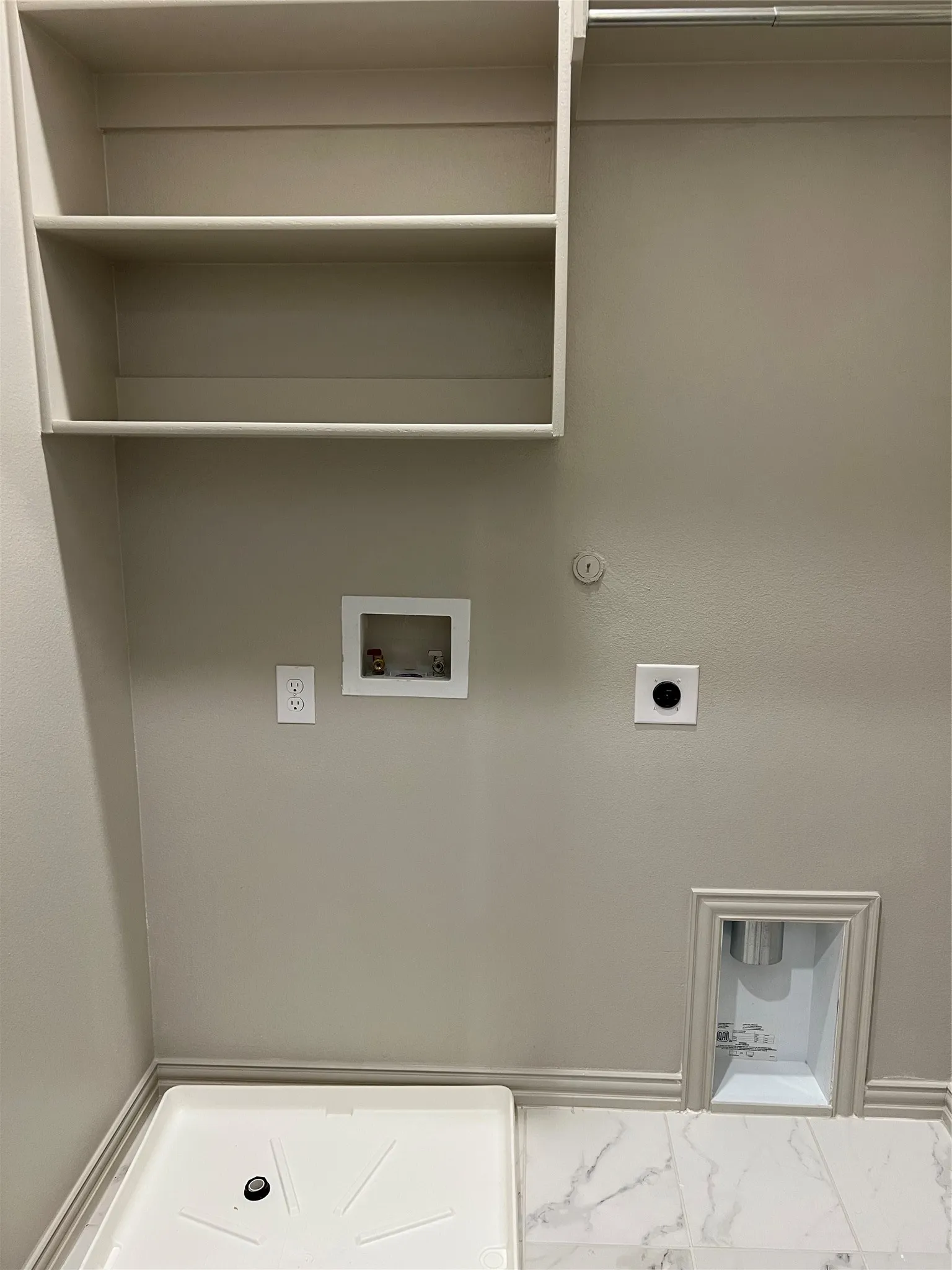 Laundry area featuring built-in shelving, a utility sink base, and marble-look flooring