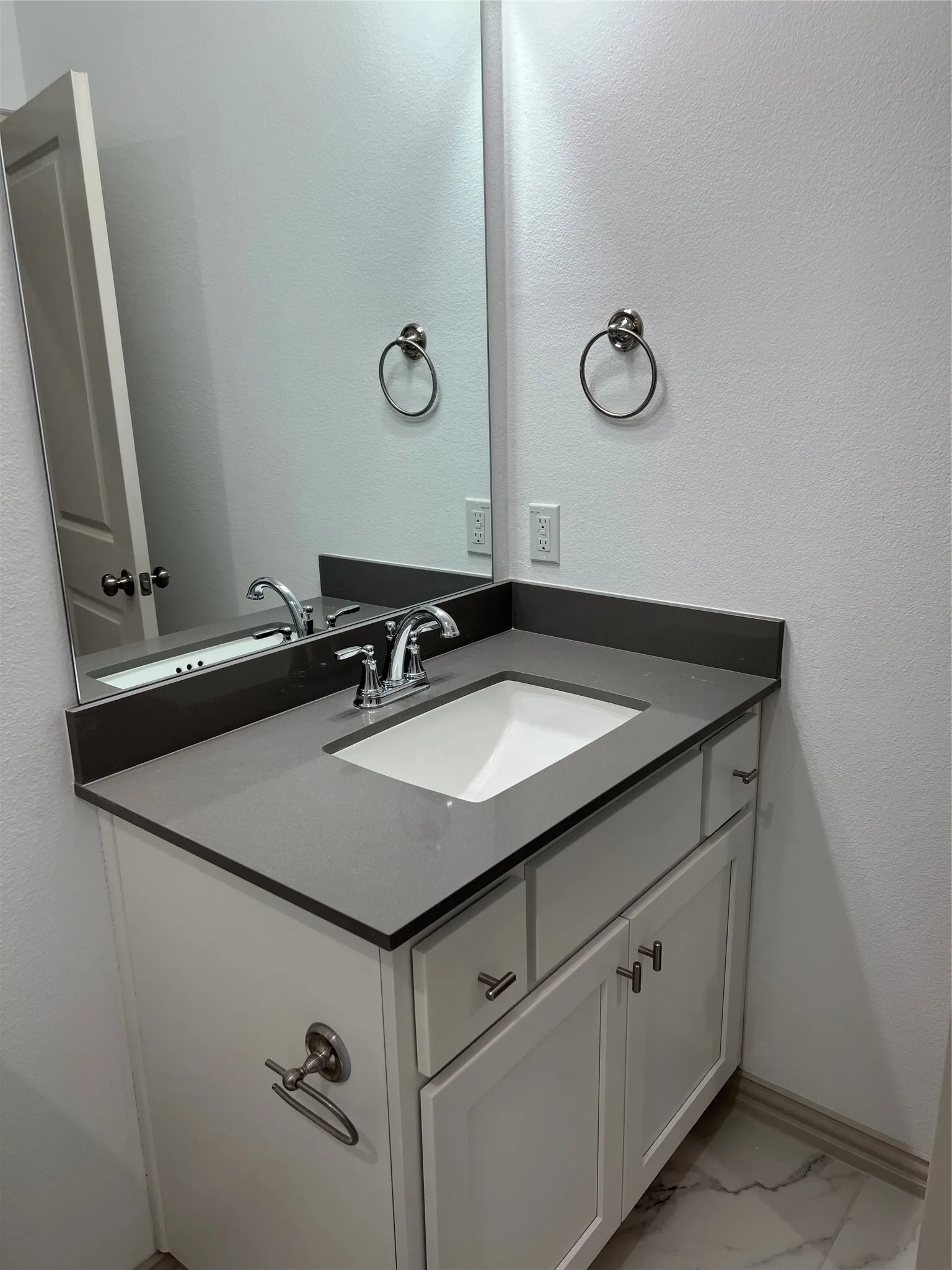 Modern vanity featuring a gray countertop, an integrated rectangular sink, and chrome-finish fixtures
