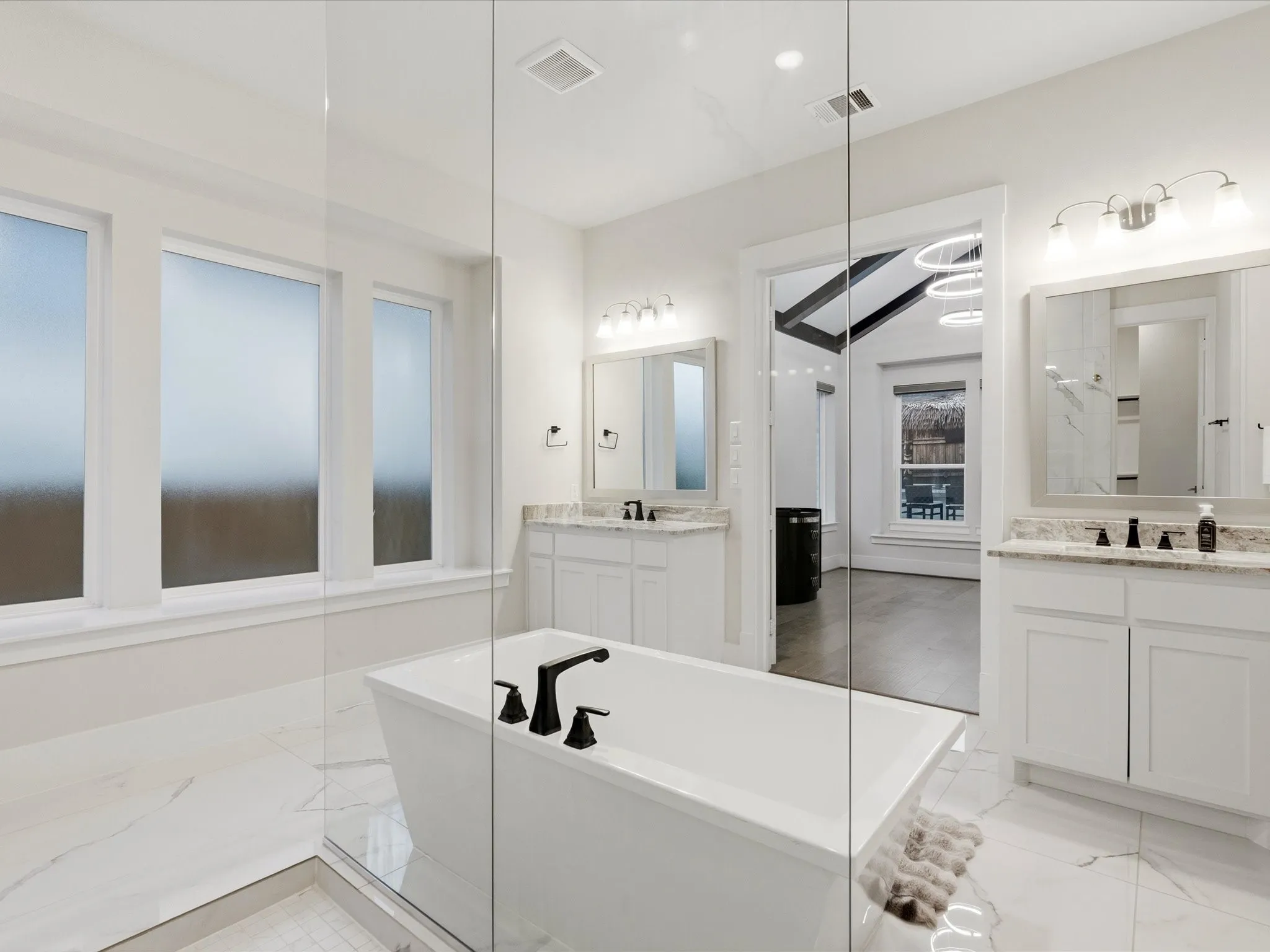 Freestanding soaking tub with matte black fixtures, set within a spacious walk-in shower featuring glass enclosure