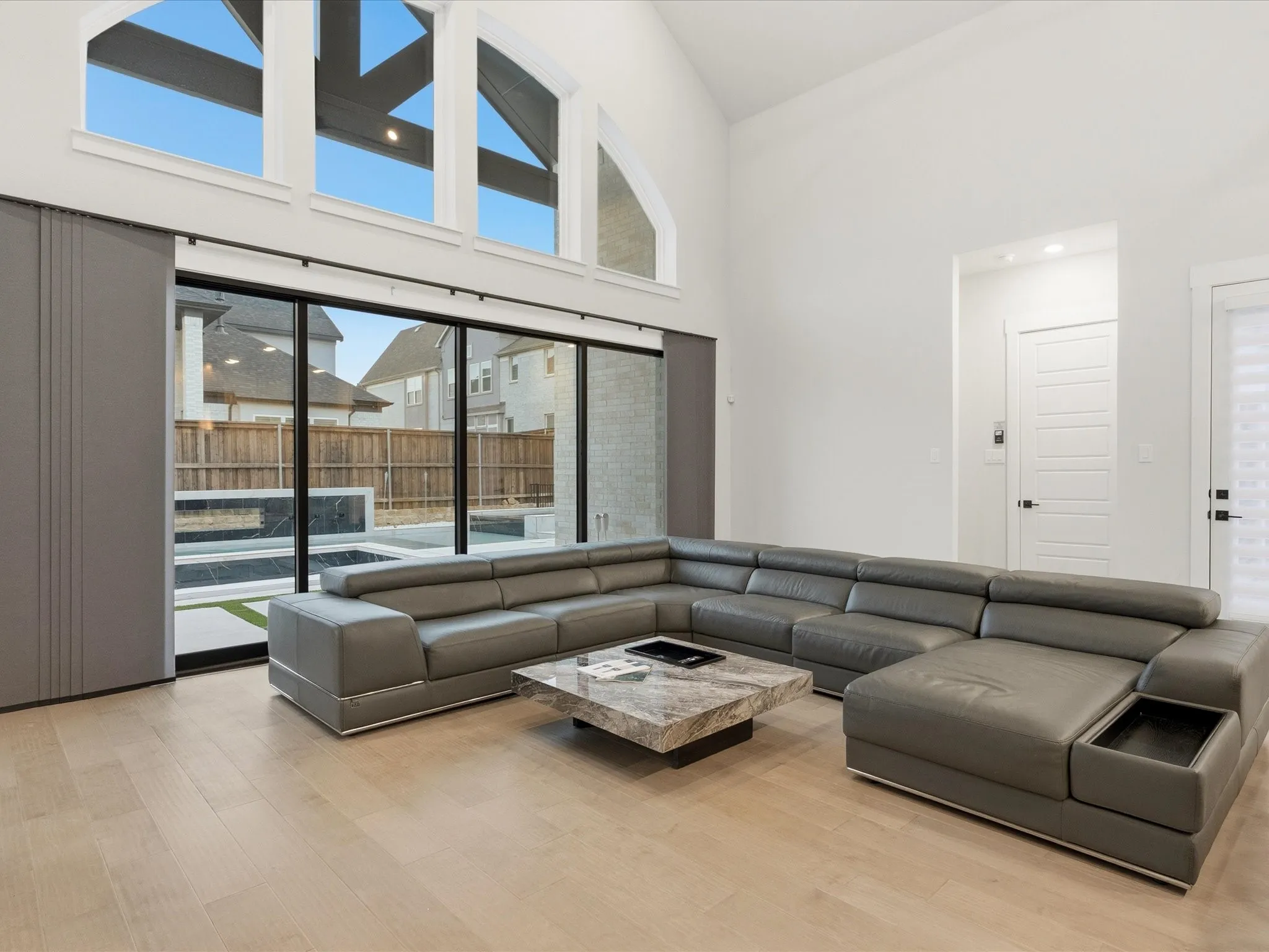 Vaulted ceilings in a living area featuring a wall of floor-to-ceiling windows, wood-finish flooring, and a modern sliding door system