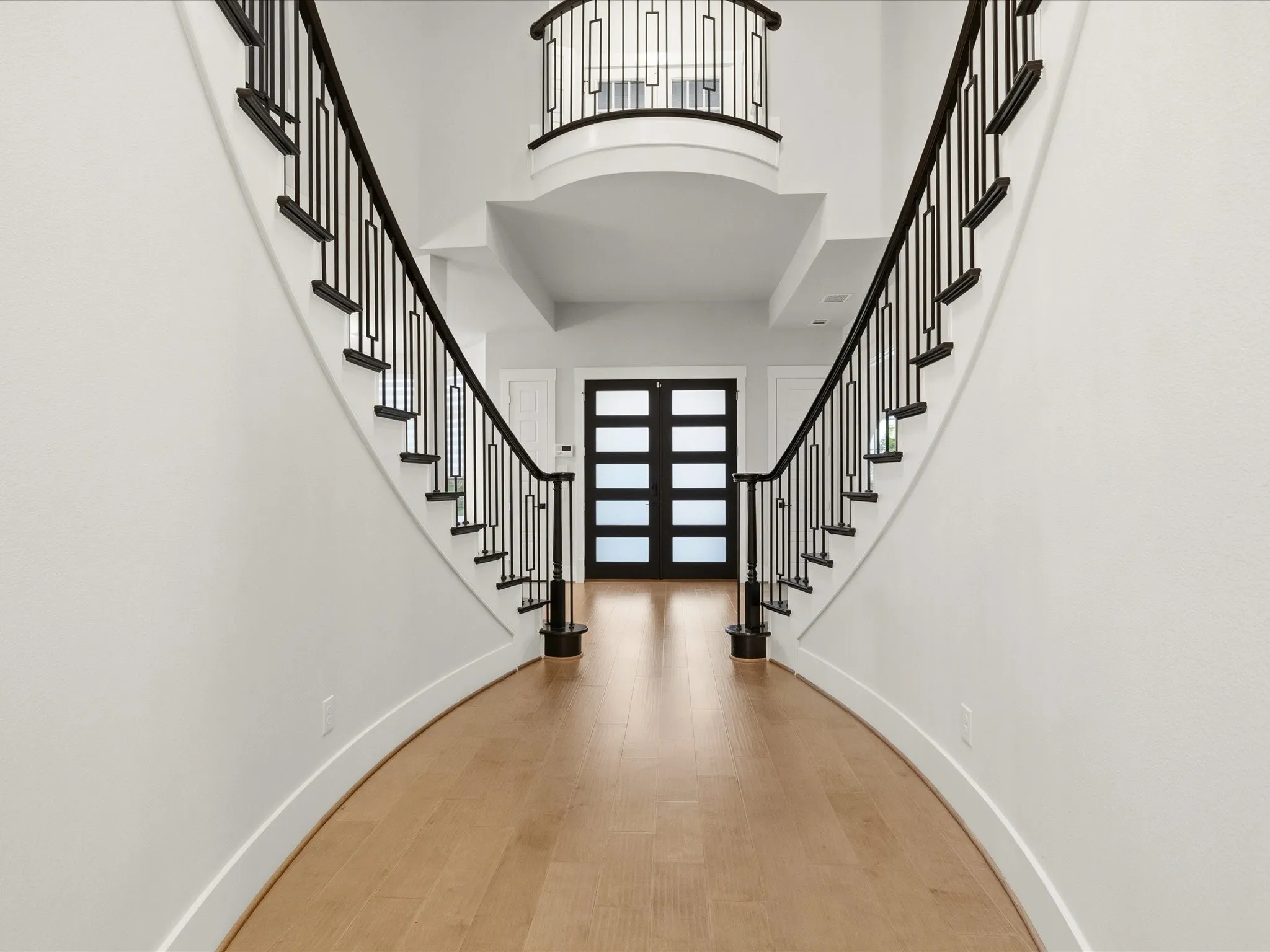 Grand entryway featuring a curved staircase with wrought iron balusters and a wood-finish flooring