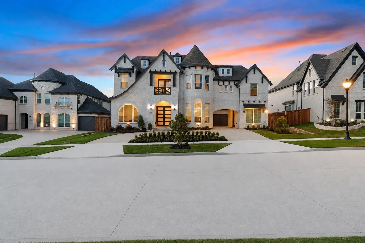 White brick exterior featuring a prominent turret, dark trim accents, multiple gables, and a contemporary glass panel entry door