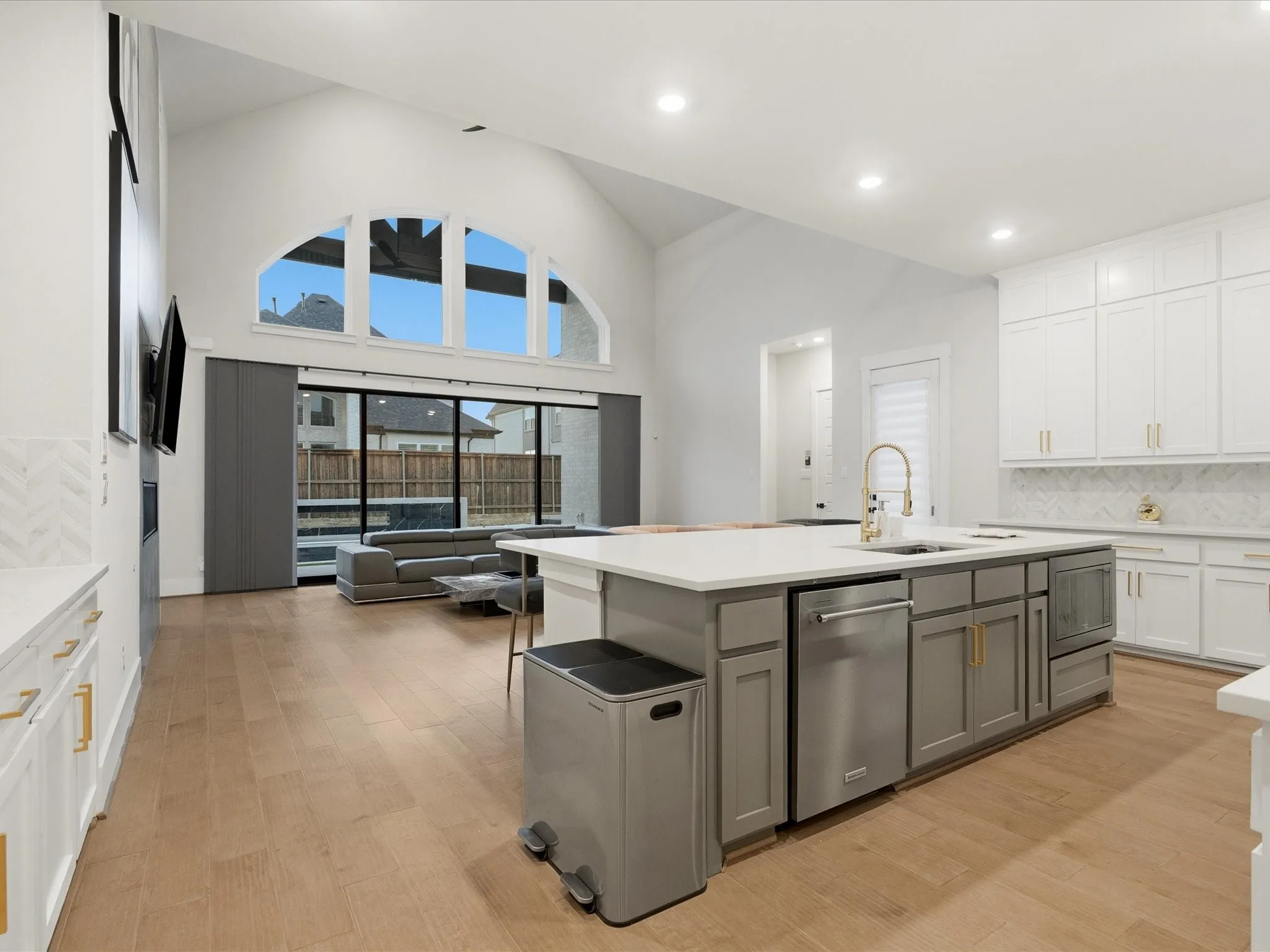 Open-concept living space featuring a spacious kitchen island with integrated sink, stainless steel dishwasher, and gold-tone faucet