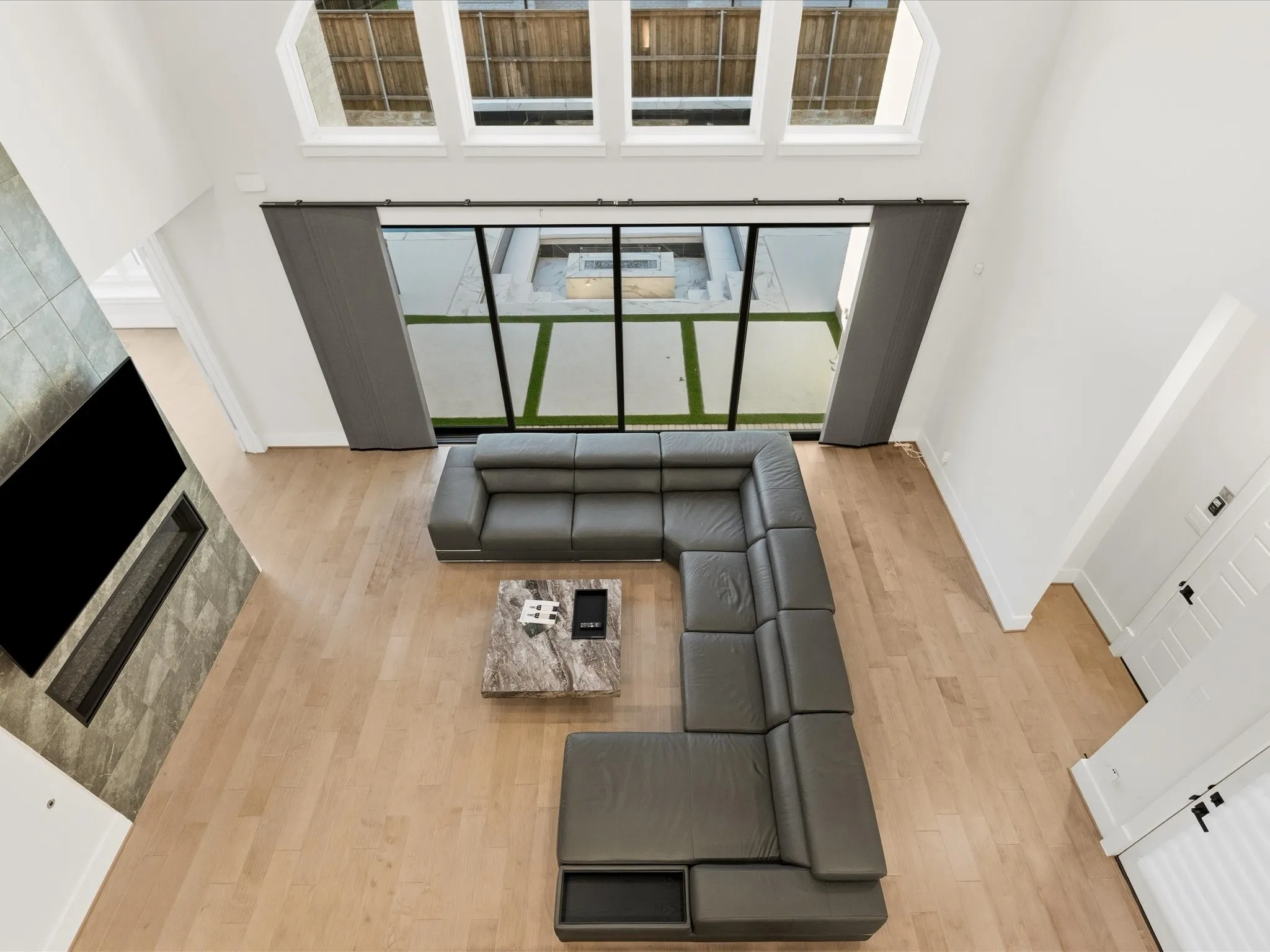 Two-story living area featuring wood-finish flooring and a tiled fireplace surround