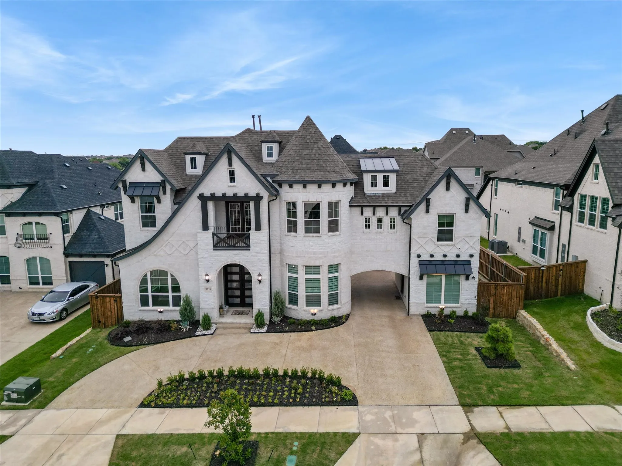 White brick exterior featuring a prominent turret, dark gabled rooflines, and a covered entryway